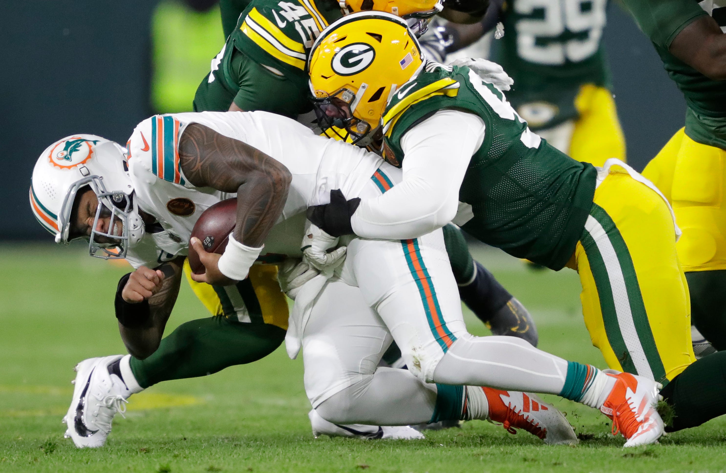 Miami Dolphins quarterback Tua Tagovailoa (1) is sacked by Green Bay Packers defensive end Lukas Van Ness (90) during their football game Thursday, November 28, 2024, at Lambeau Field in Green Bay, Wisconsin.