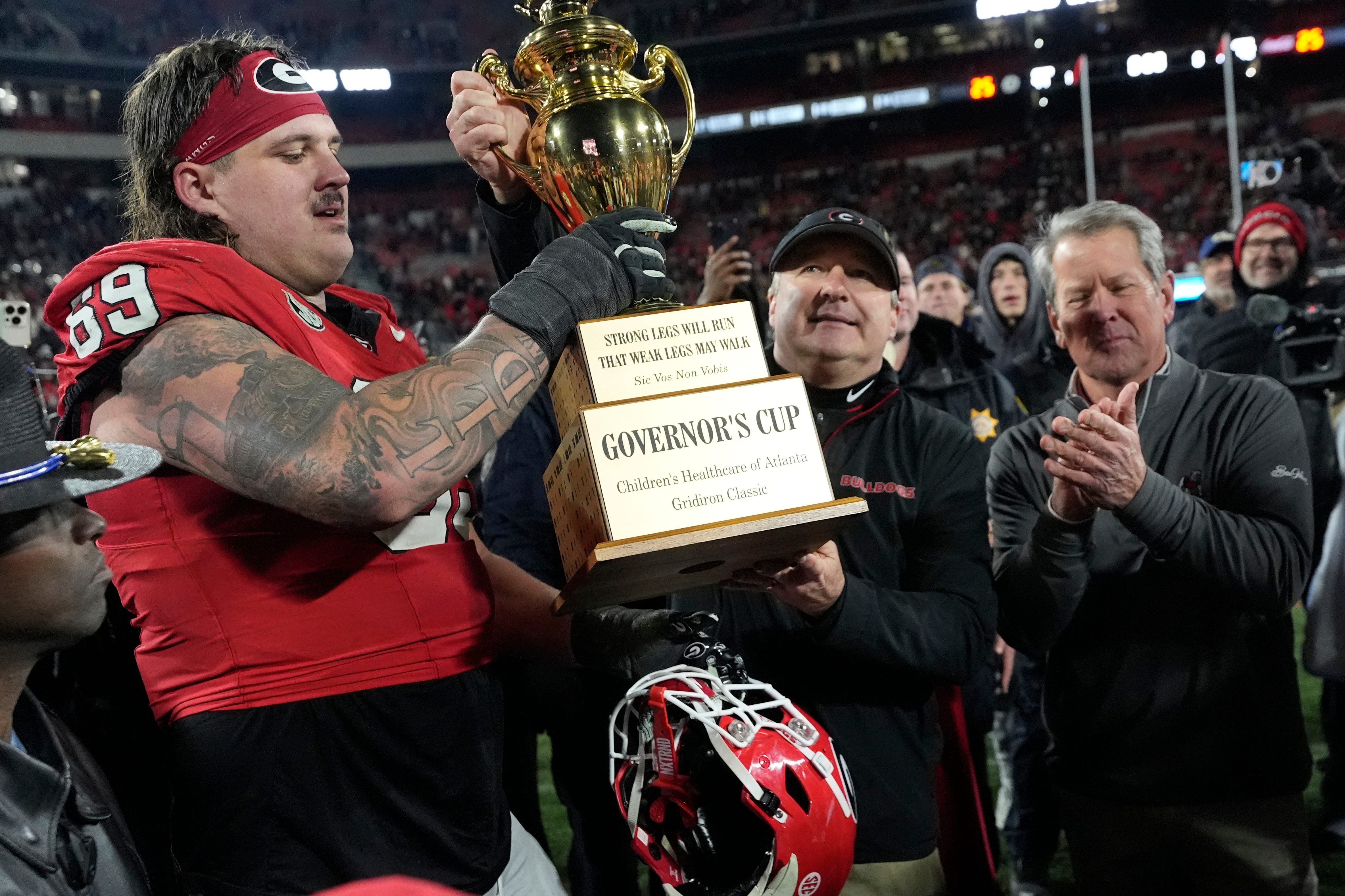 Georgia coach Kirby Smart hands the governor cup to Georgia offensive lineman Tate Ratledge (69) after Georgia won a NCAA college football game against Georgia Tech in overtime in Athens, Ga., on Friday.