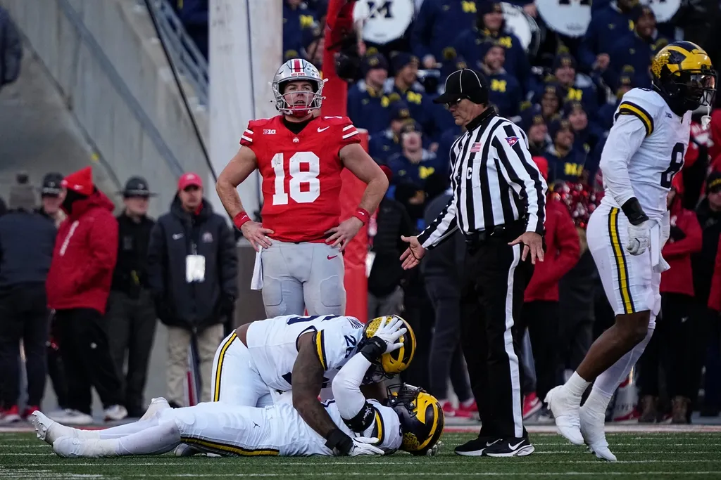 Ohio State quarterback Will Howard (18) reacts as Michigan players celebrate a fourth-down stop to seal the game during the fourth quarter at Ohio Stadium in Columbus on Saturday, Nov. 30, 2024