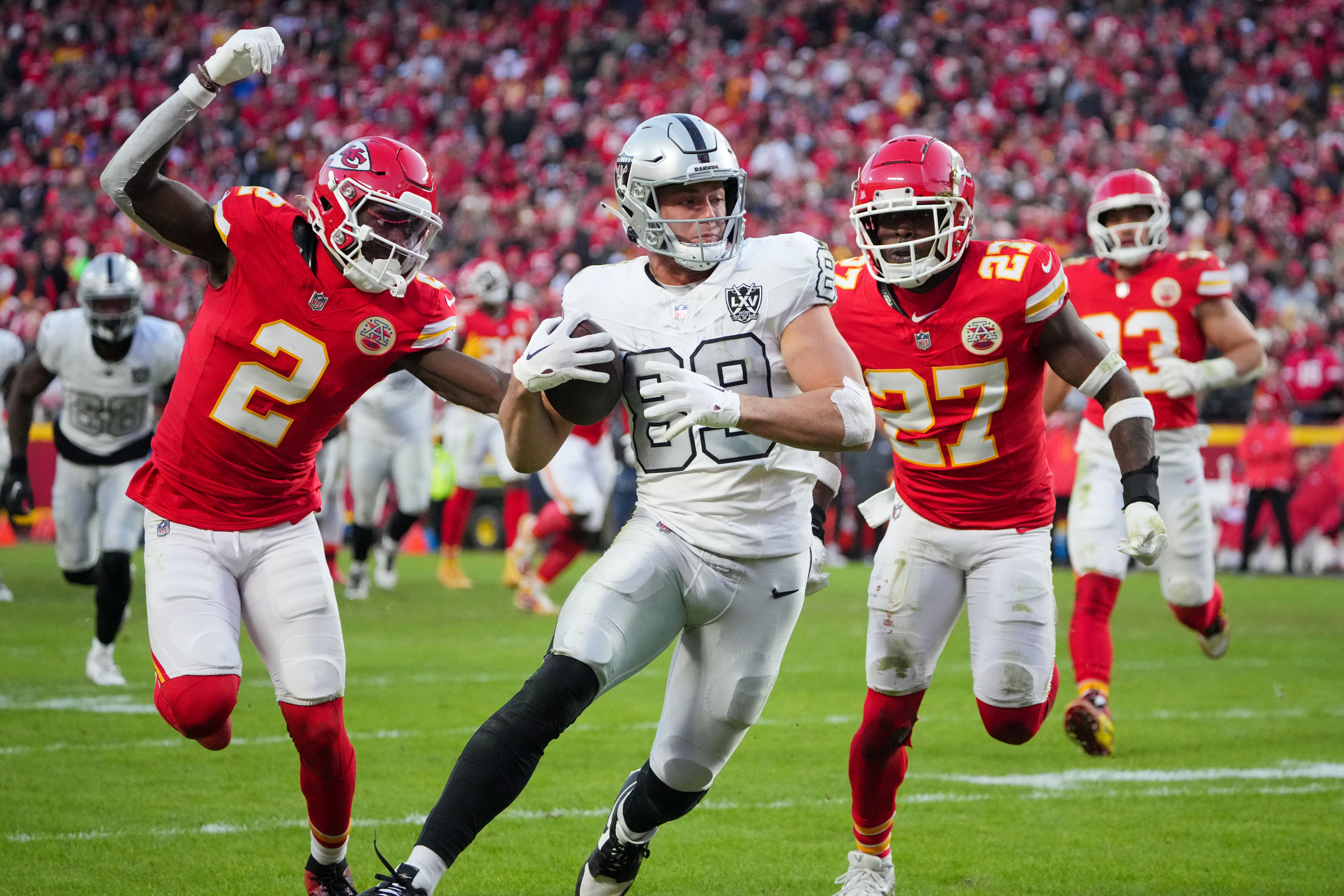 Nov 29, 2024; Kansas City, Missouri, USA; Las Vegas Raiders tight end Brock Bowers (89) scores a touchdown as Kansas City Chiefs cornerback Joshua Williams (2) and safety Chamarri Conner (27) chase during the second half at GEHA Field at Arrowhead Stadium.