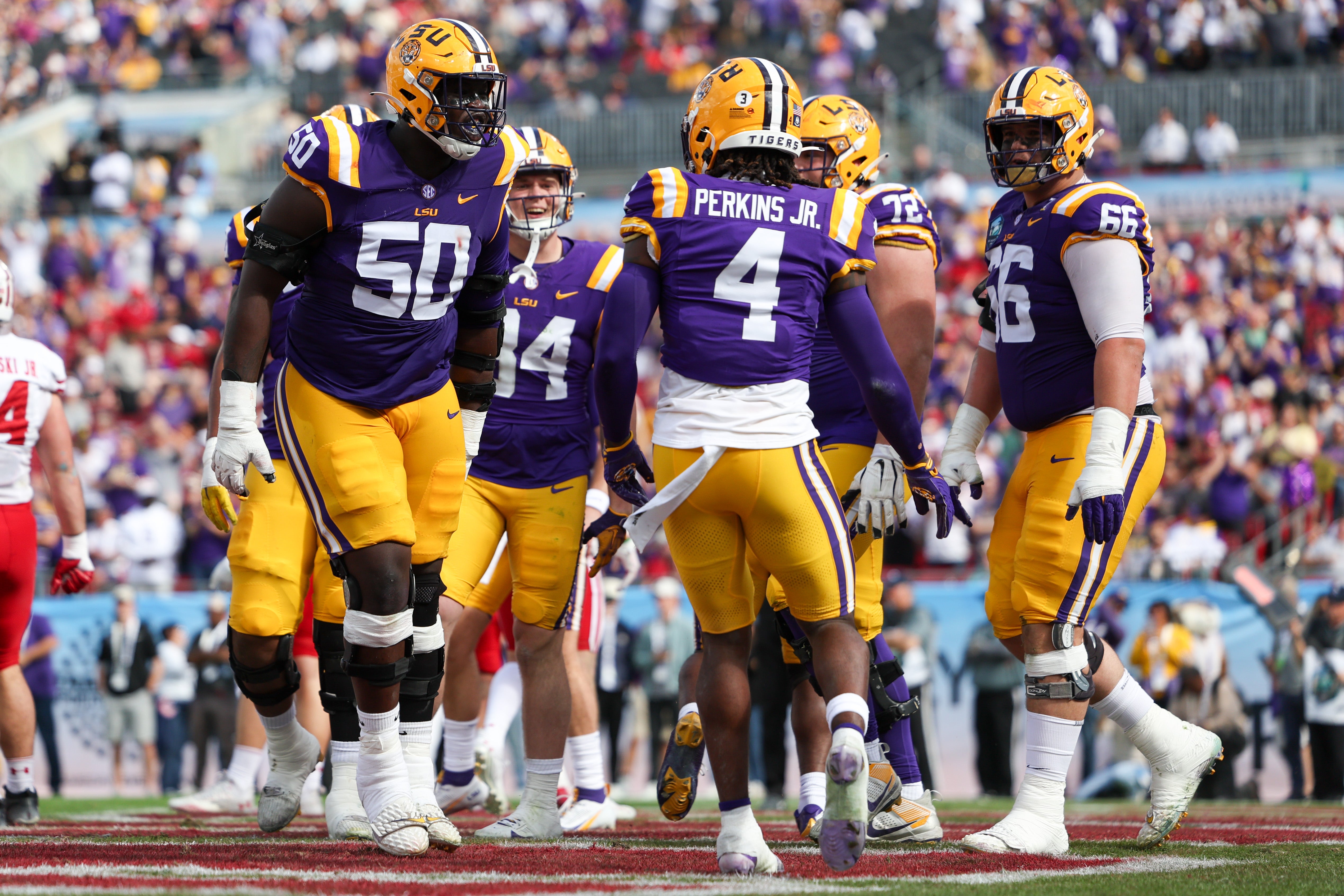 LSU Tigers offensive lineman Emery Jones Jr. (50) celebrates with running back John Emery Jr. (4) after scoring a touchdownagainst the Wisconsin Badgers in the second quarter during the ReliaQuest Bowl at Raymond James Stadium.