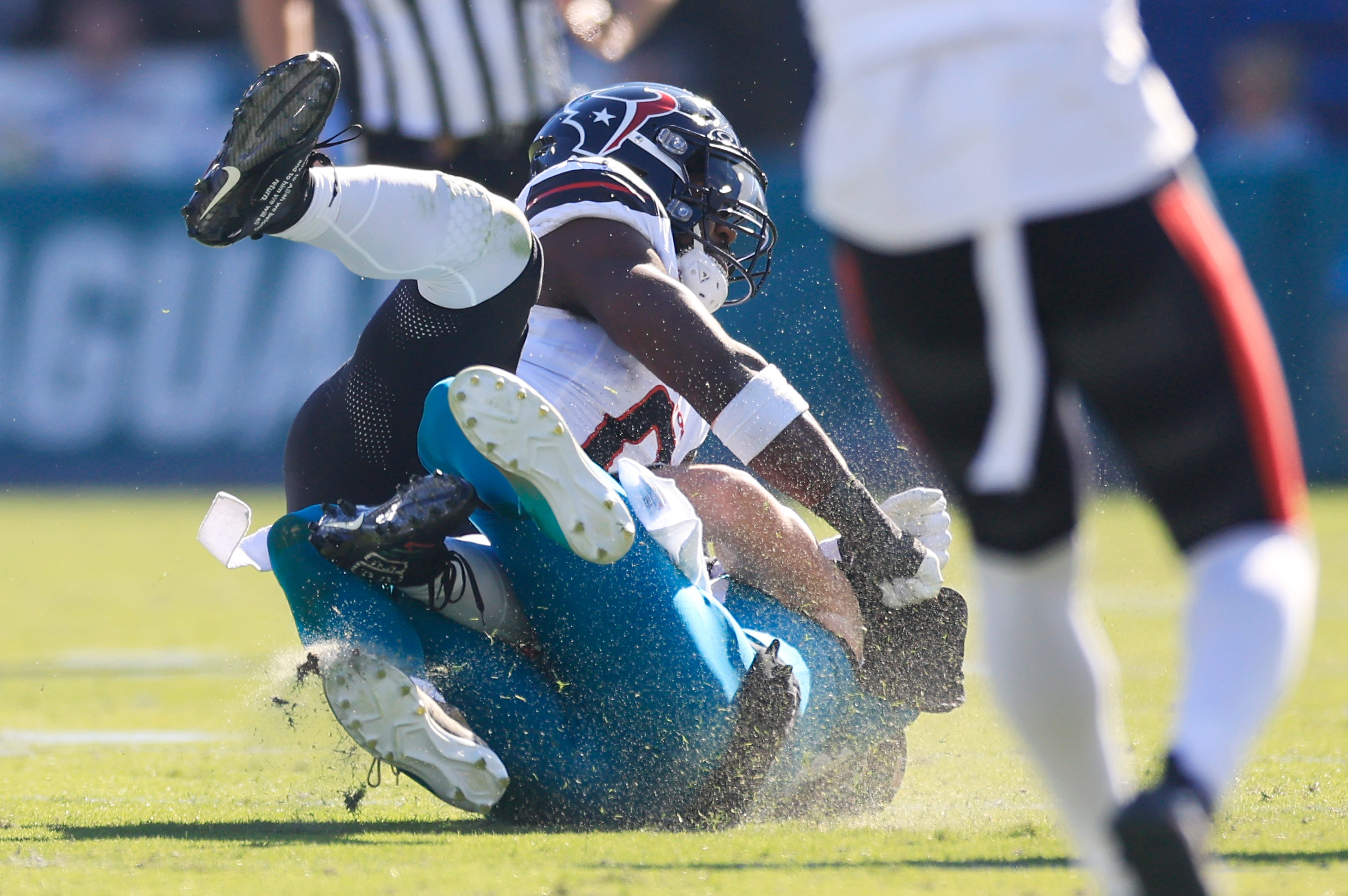 Jacksonville Jaguars quarterback Trevor Lawrence (16) slides for a down as Houston Texans linebacker Azeez Al-Shaair (0) makes a late hit during the second quarter of an NFL football matchup Sunday, Dec. 1, 2024 at EverBank Stadium in Jacksonville, Fla.