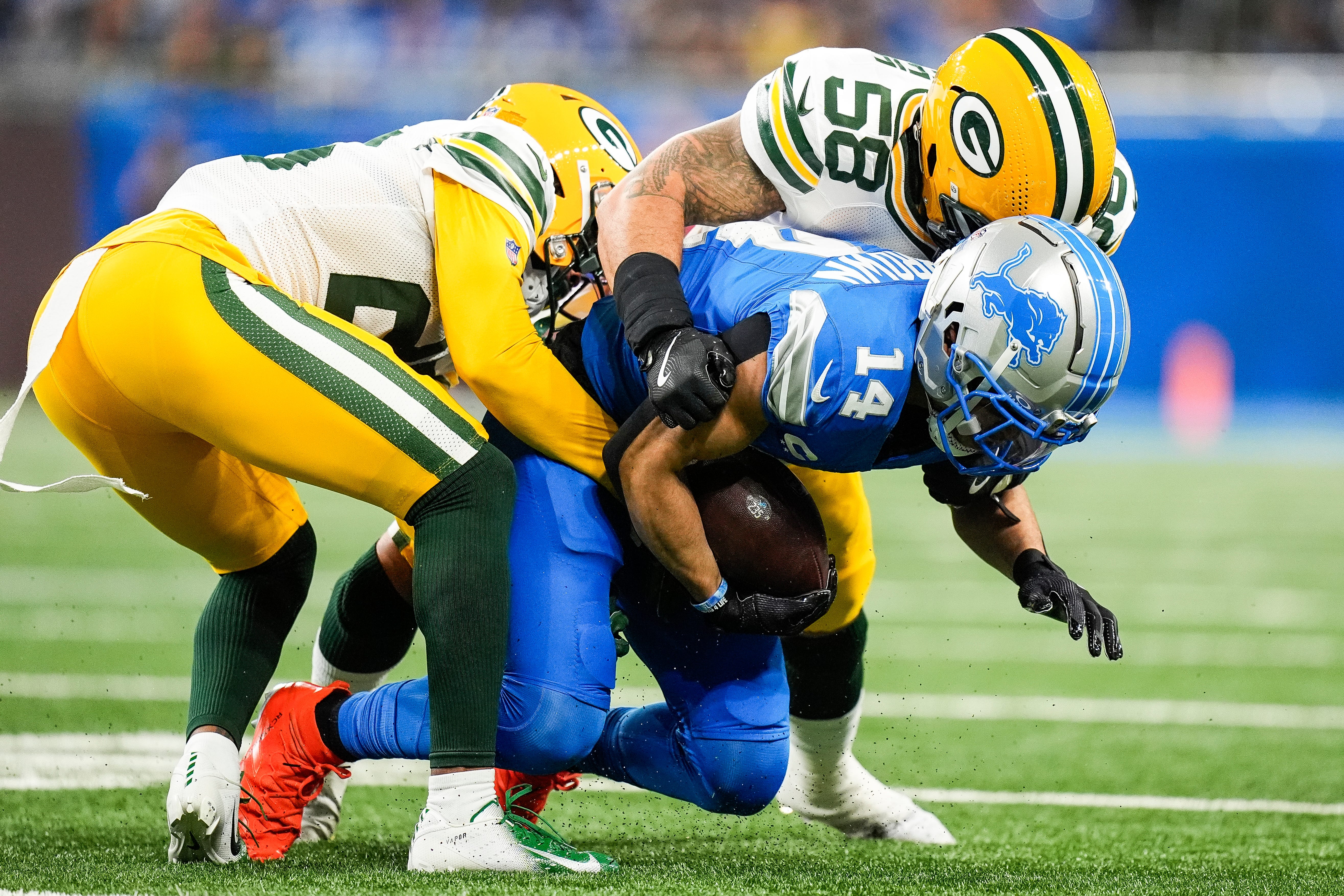 Detroit Lions wide receiver Amon-Ra St. Brown (14) makes a catch against Green Bay Packers cornerback Corey Ballentine (26), left, and linebacker Isaiah McDuffie (58) during the first half at Ford Field in Detroit on Thursday, Dec. 5, 2024.