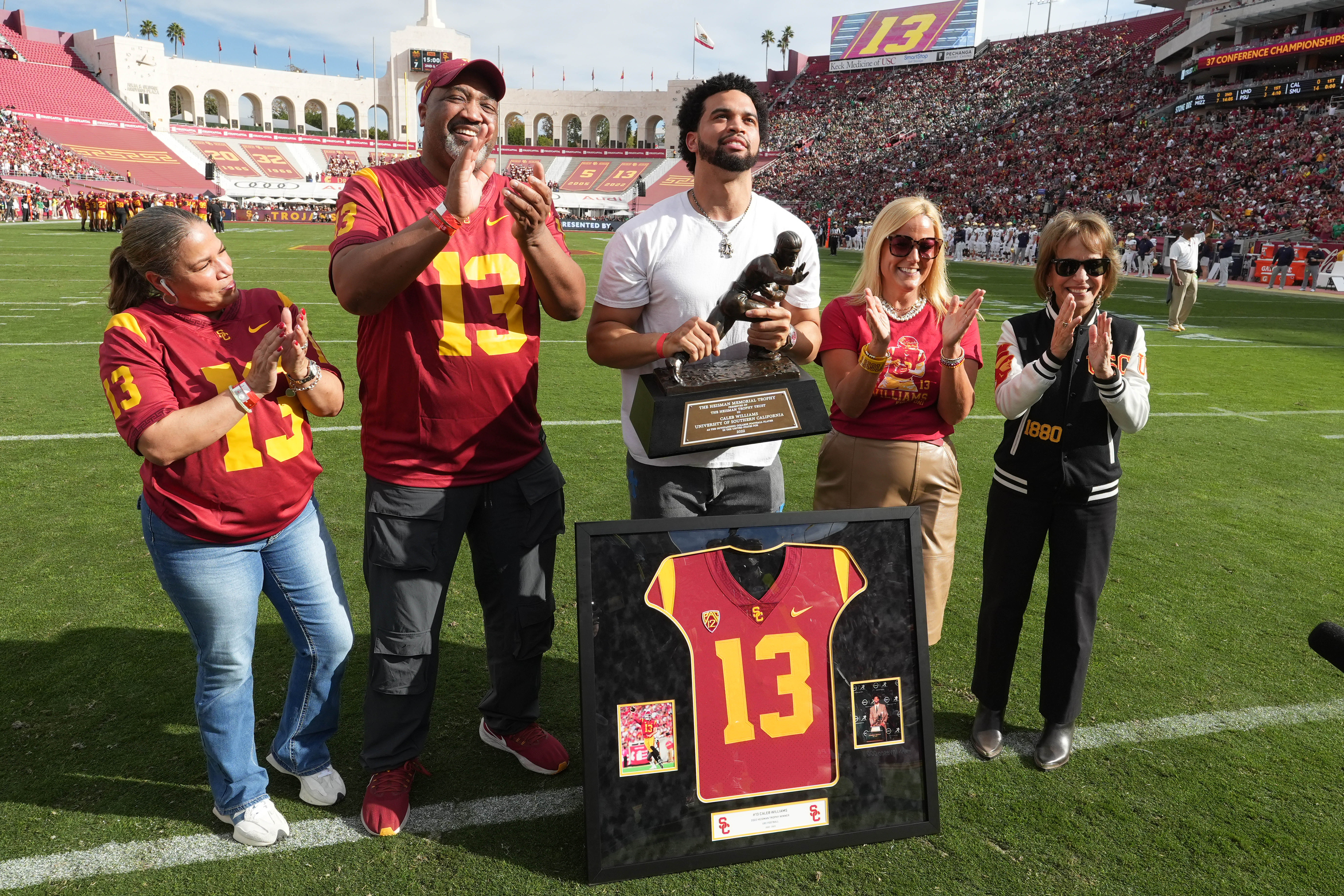 Nov 30, 2024; Los Angeles, California, USA; Chicago Bears and former Southern California Trojans quarterback Caleb Williams (center) holds Heisman Trophy and poses (from left) mother Dayne Price, father Carl Williams, athletic director Jennifer Cohen and president Carol Folt during jersey retirement ceremony at United Airlines Field at Los Angeles Memorial Coliseum.