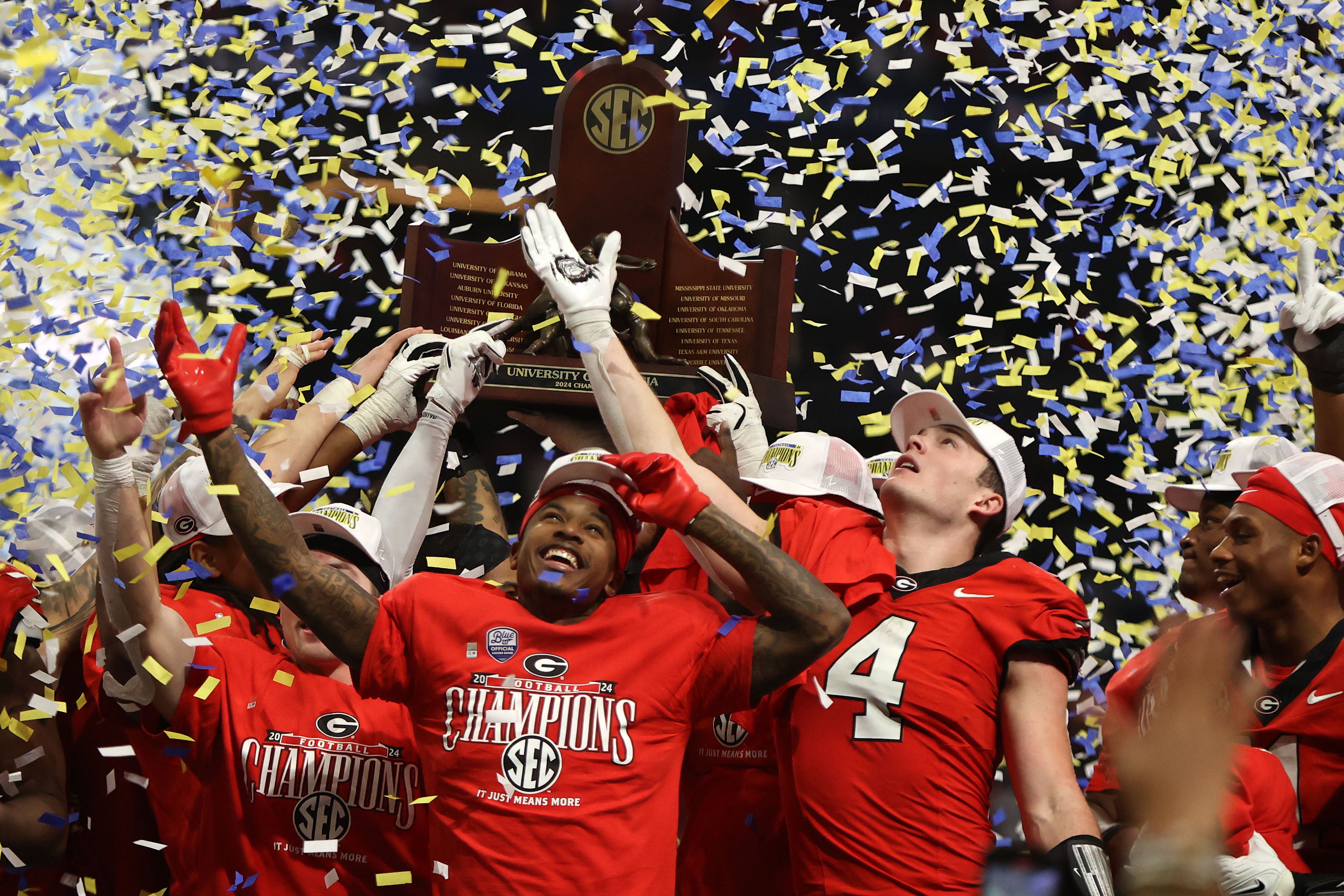 The Georgia Bulldogs celebrate with the trophy after defeating the Texas Longhorns in overtime in the 2024 SEC Championship game at Mercedes-Benz Stadium.