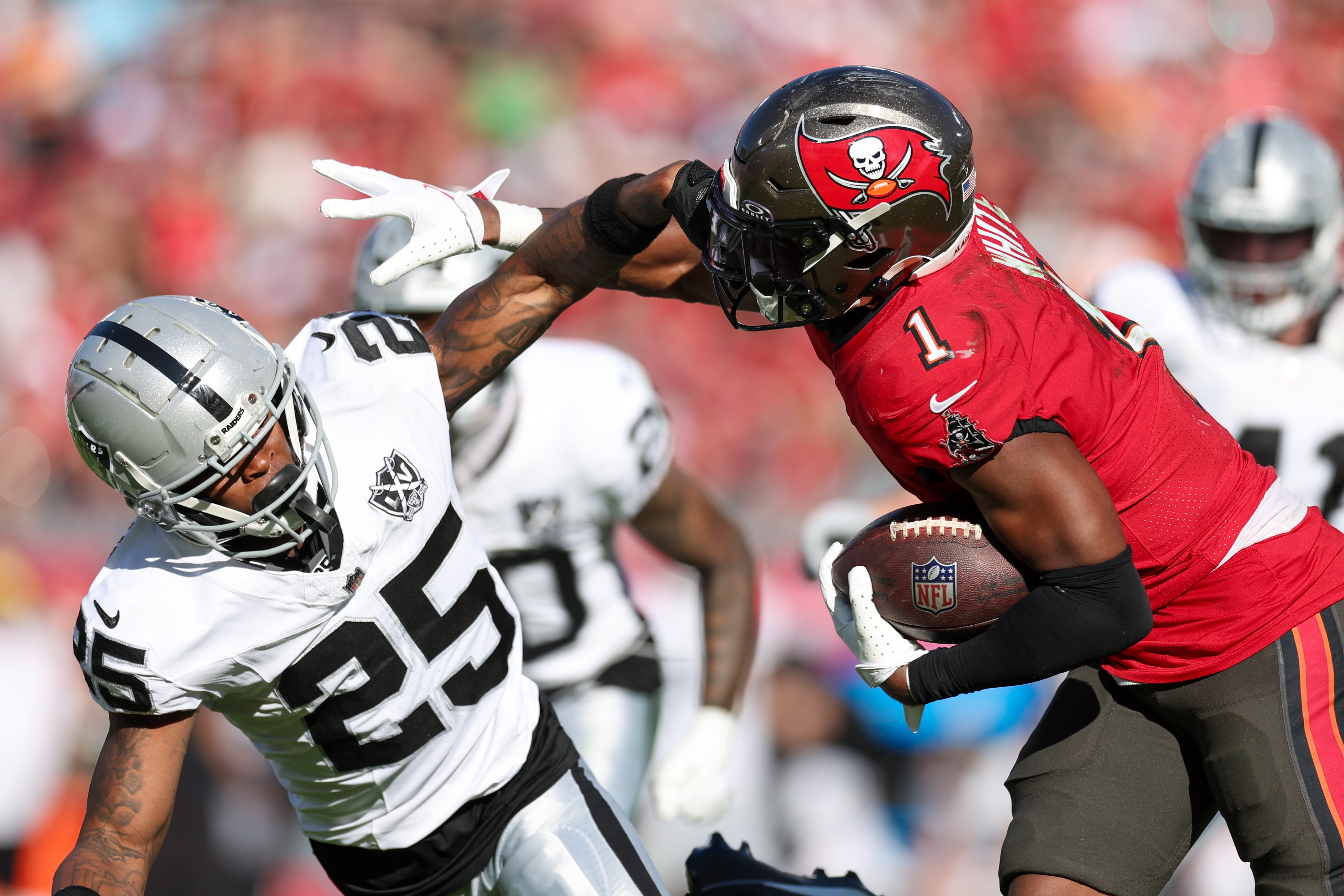 Dec 8, 2024; Tampa, Florida, USA; Tampa Bay Buccaneers running back Rachaad White (1) holds off Las Vegas Raiders cornerback Decamerion Richardson (25) in the third quarter at Raymond James Stadium.