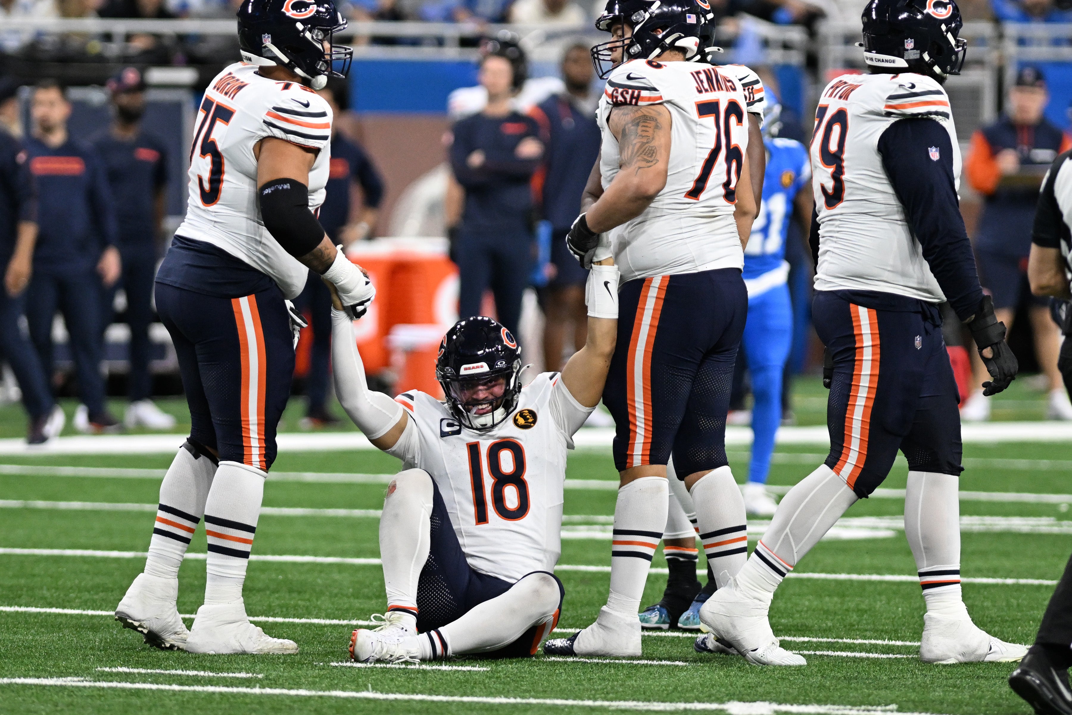 Nov 28, 2024; Detroit, Michigan, USA; Chicago Bears quarterback Caleb Williams (18) gets helped off the turf by offensive tackle Larry Borom (75) and guard Teven Jenkins (76) in the fourth quarter against the Detroit Lions at Ford Field.