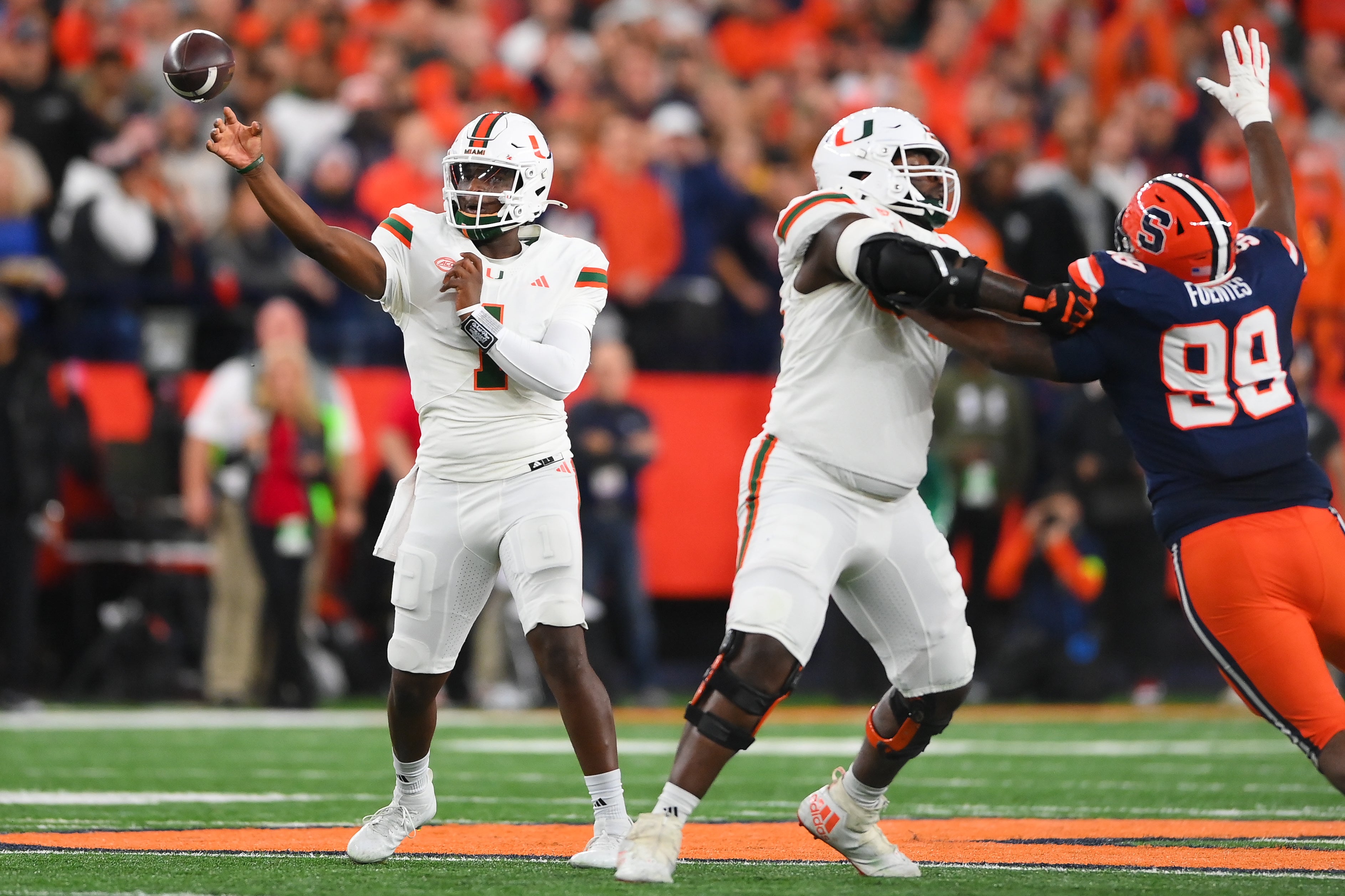 Miami Hurricanes quarterback Cam Ward (1) passes the ball as Syracuse Orange defensive lineman Elijah Fuentes-Cundiff (99) pressures during the first half at the JMA Wireless Dome.