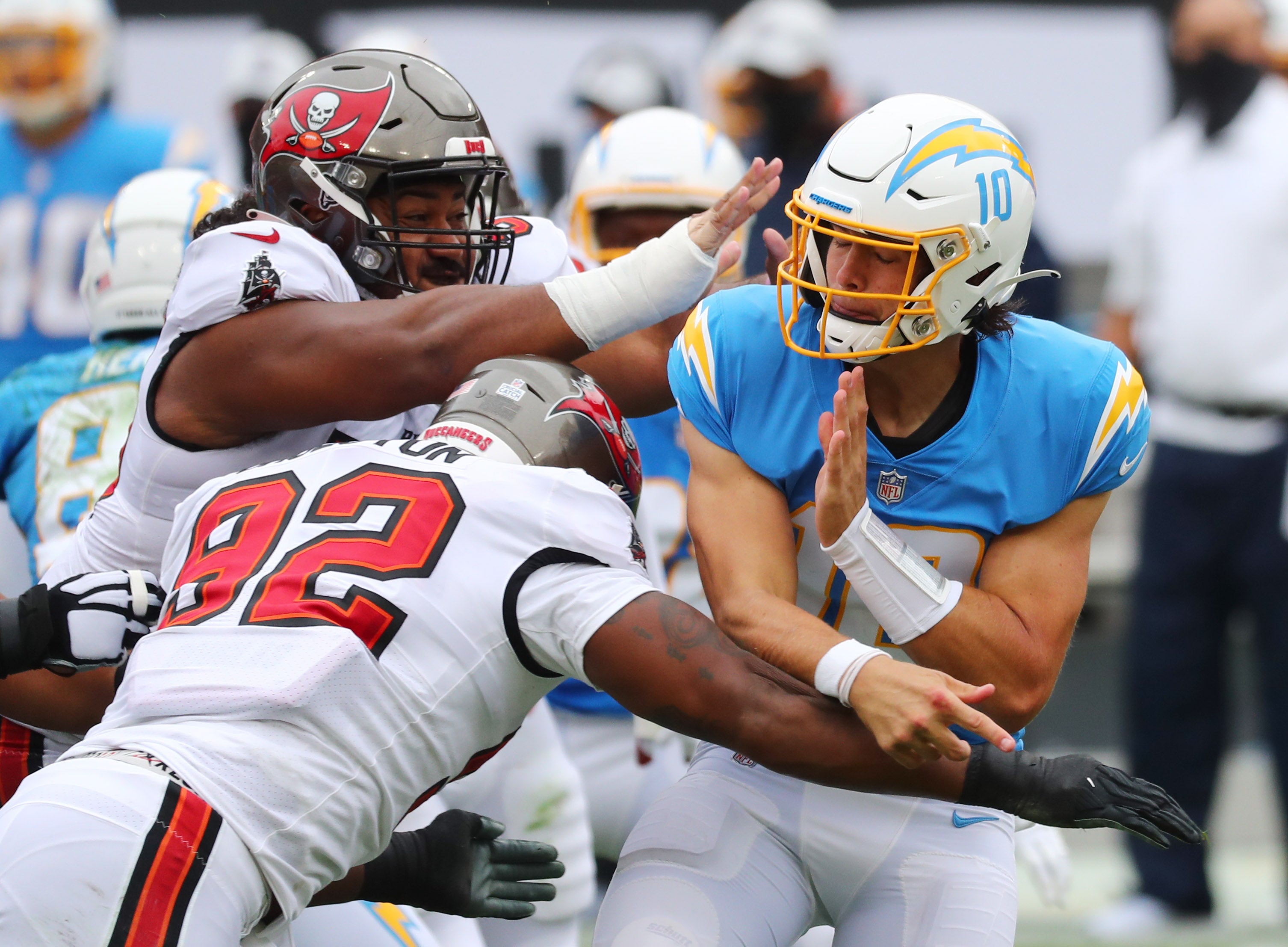 Oct 4, 2020; Tampa, Florida, USA; Los Angeles Chargers quarterback Justin Herbert (10) is hit by Tampa Bay Buccaneers defensive end William Gholston (92) as he throws a pass in the first quarter of a NFL game at Raymond James Stadium.