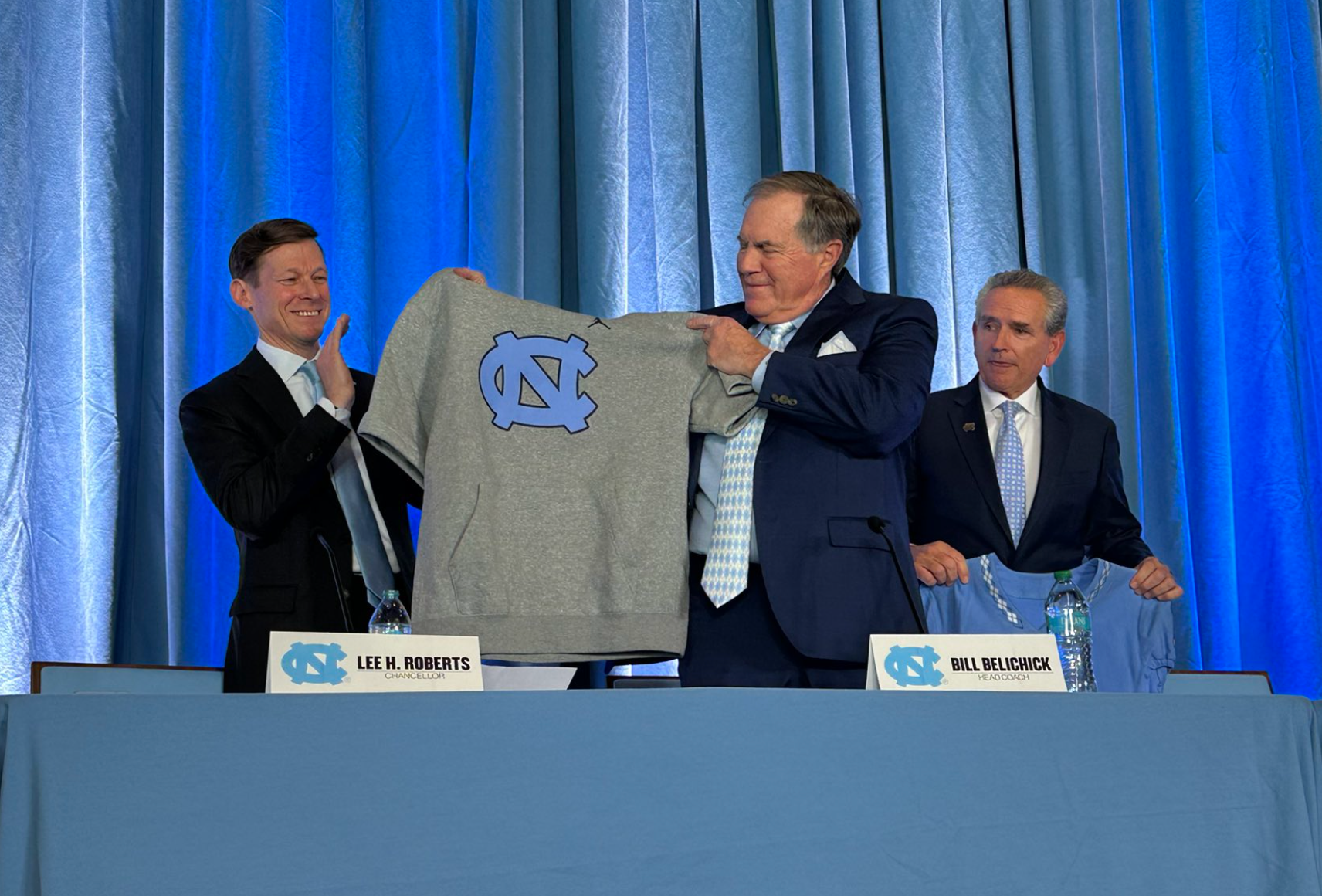 Bill Belichick holding up a cutoff hoodie during his introductory press conference at the University of North Carolina