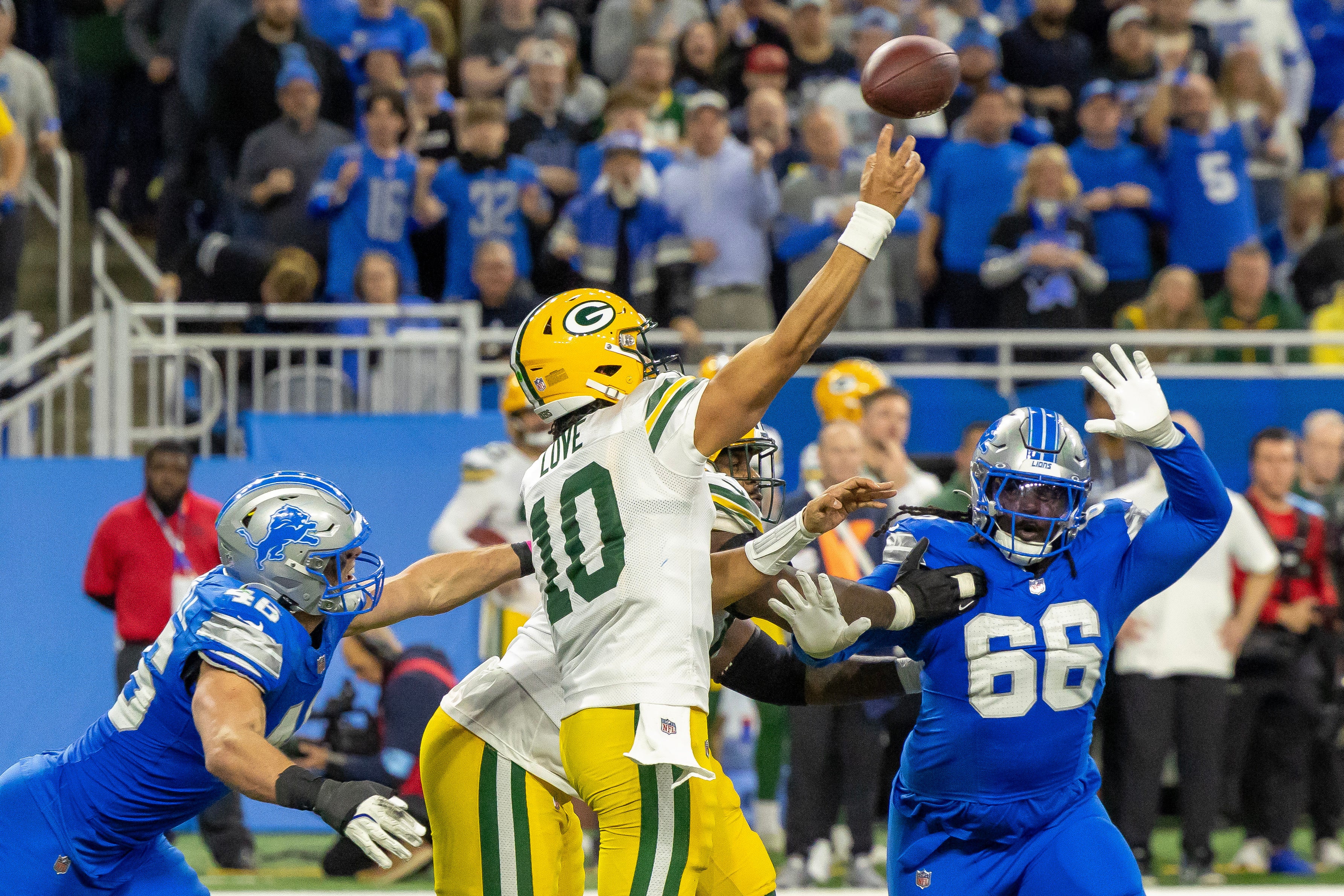 Green Bay Packers quarterback Jordan Love (10) completes a long pass while being pressured by Detroit Lions linebacker Jack Campbell (46) and defensive lineman Myles Adams (66) during the fourth quarter at Ford Field.