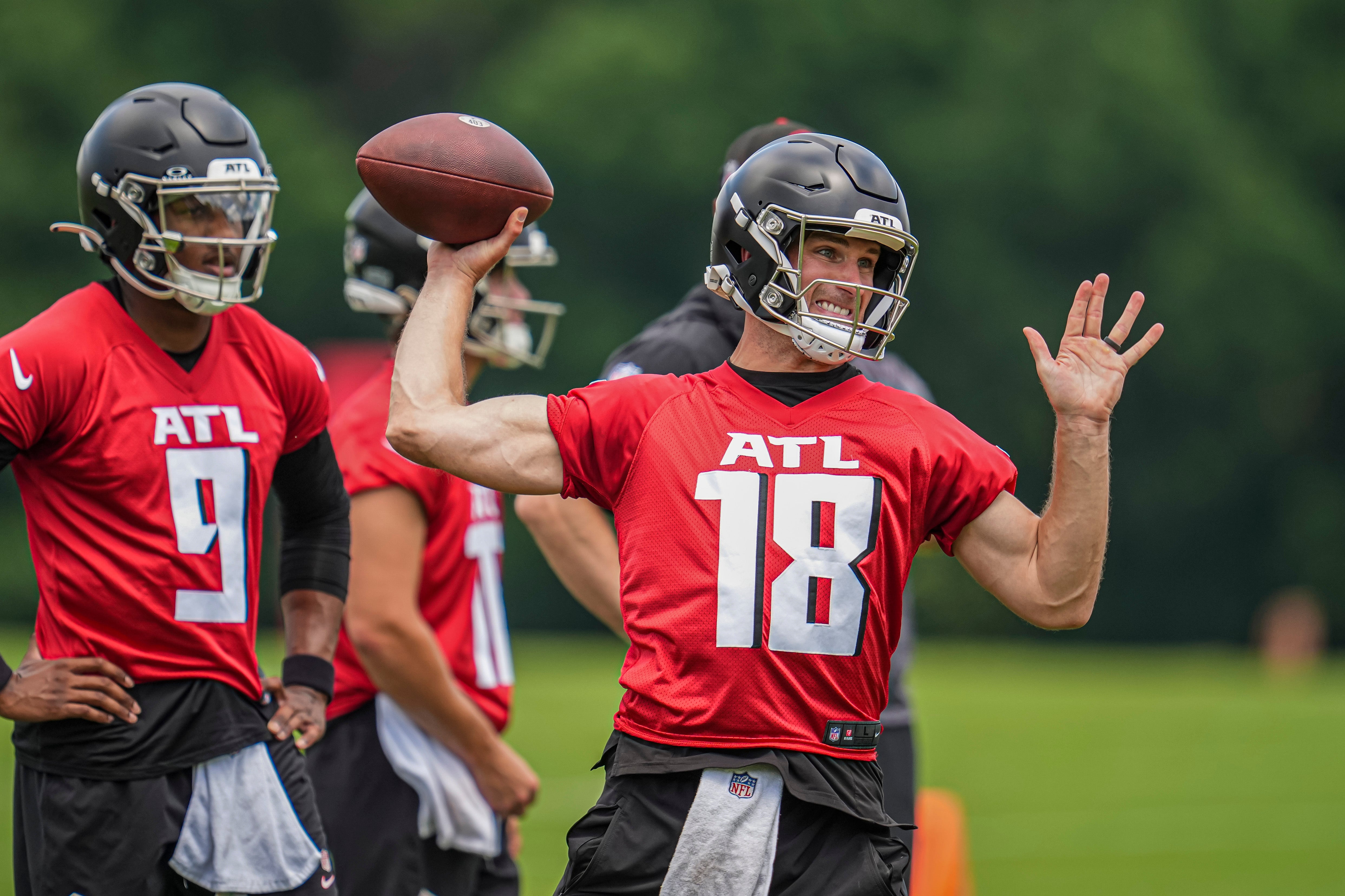 Jun 3, 2024; Atlanta, GA, USA; Atlanta Falcons quarterback Kirk Cousins (18) throws while quarterback Michael Penix Jr (9) watches on the field during Falcons OTA at the Falcons Training facility.