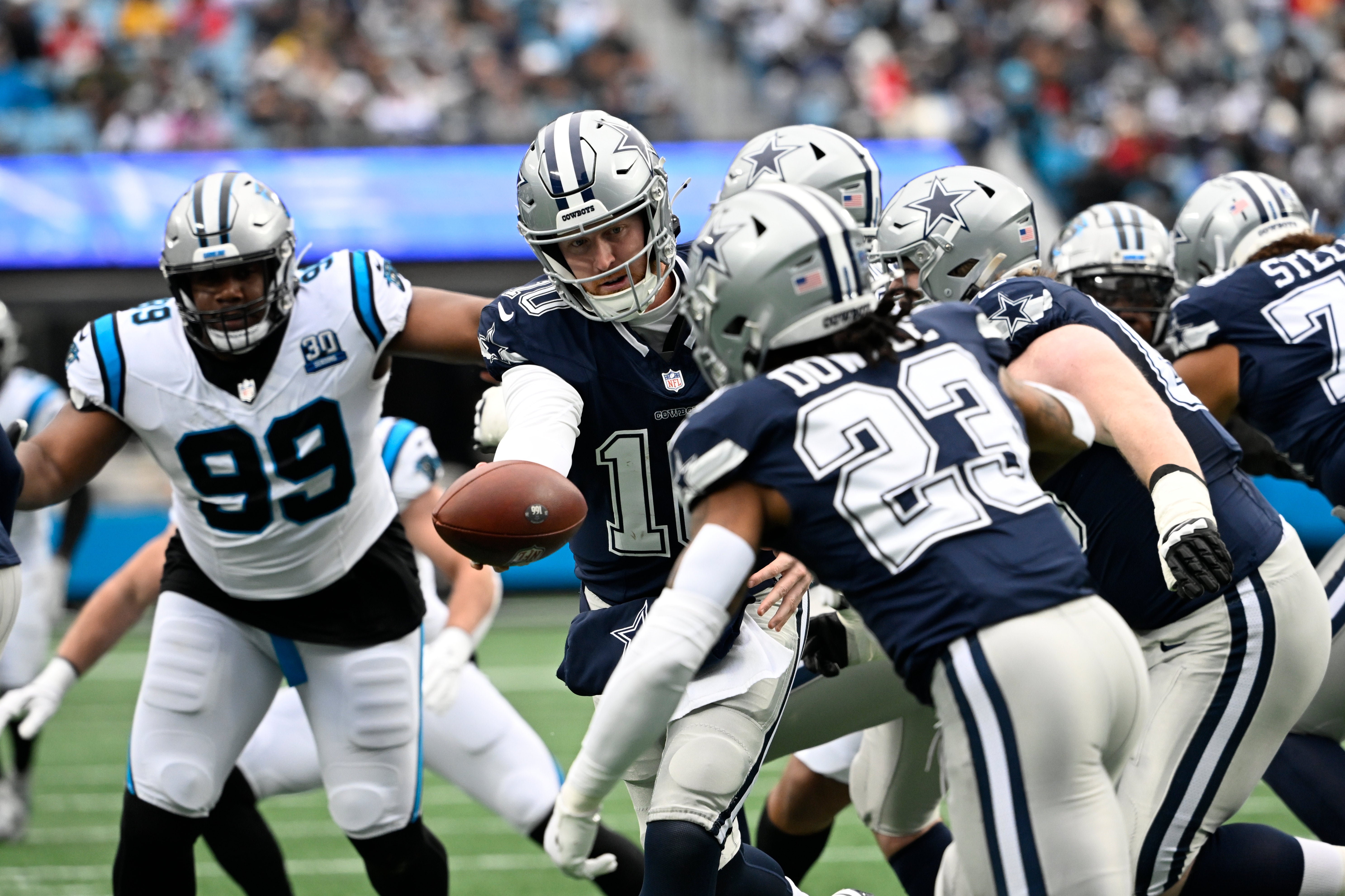 Dallas Cowboys quarterback Cooper Rush (10) fakes the hand off to running back Rico Dowdle (23) in the first quarter at Bank of America Stadium.