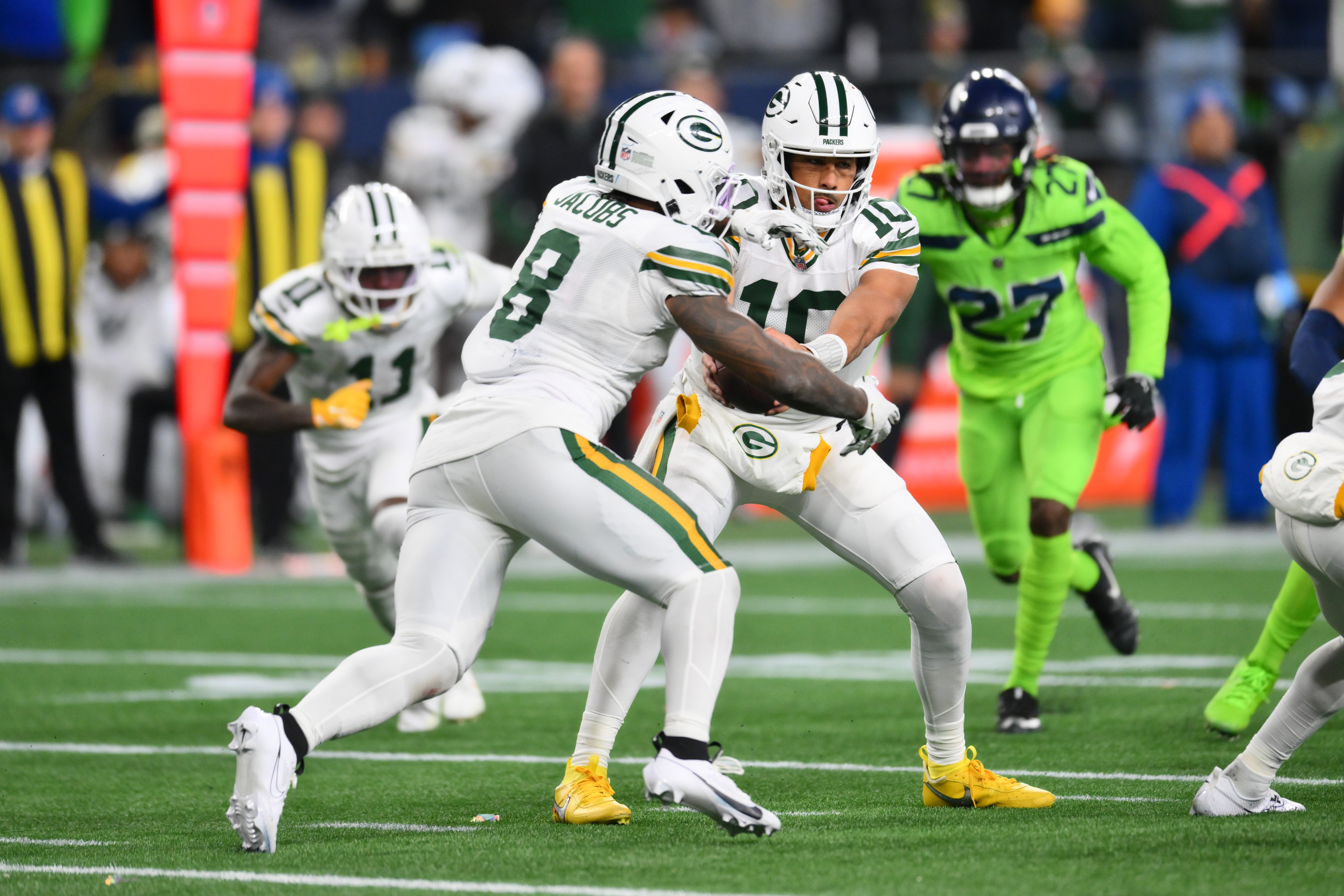 Green Bay Packers quarterback Jordan Love (10) hands the ball off to running back Josh Jacobs (8) during the second half against the Seattle Seahawks at Lumen Field.