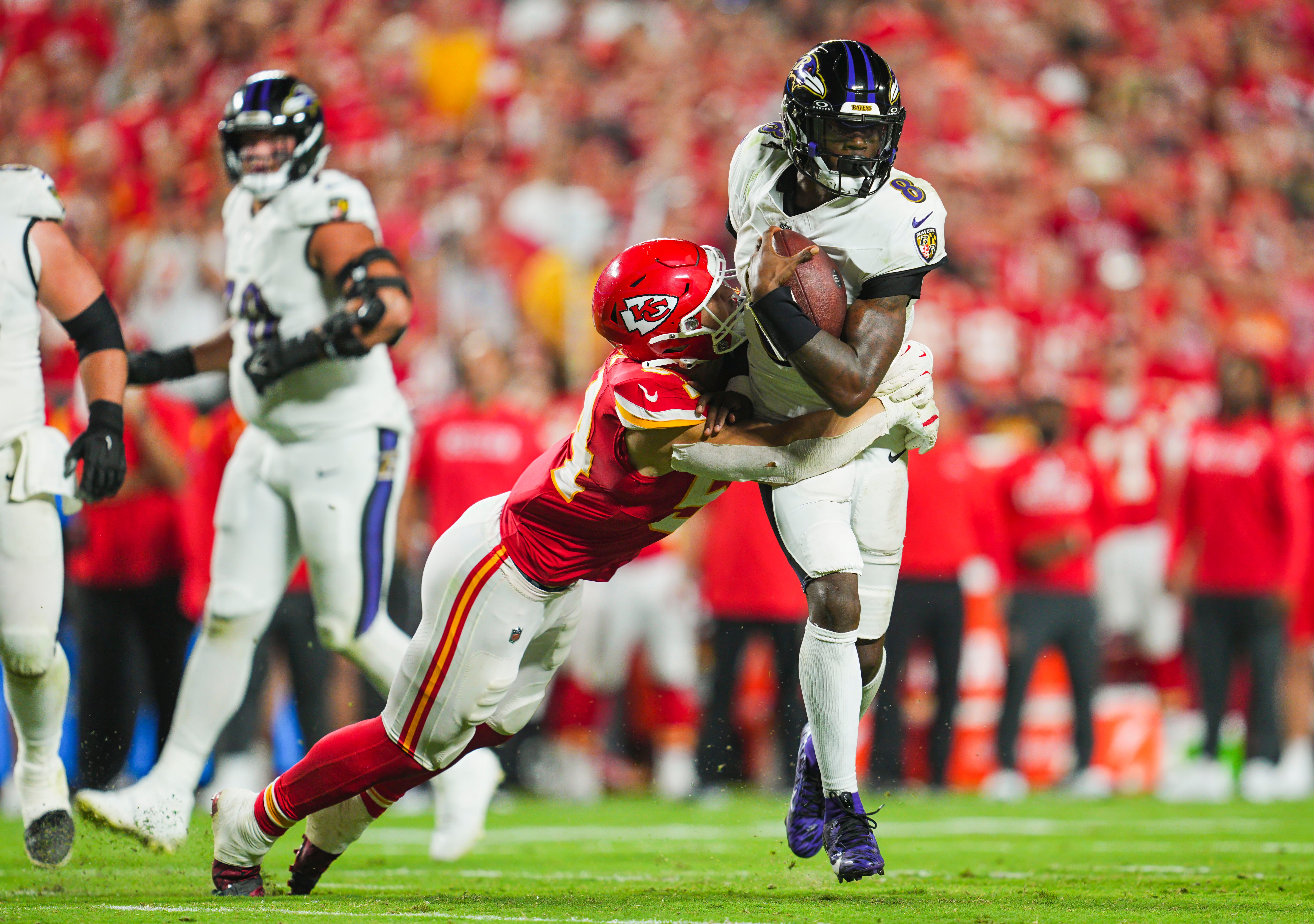 Ravens quarterback Lamar Jackson (8) is tackled by Chiefs linebacker Leo Chenal (54)