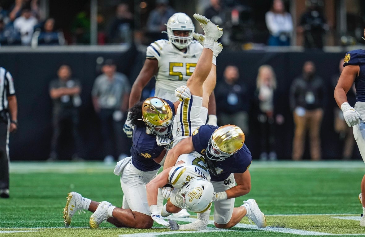 Georgia Tech Yellow Jackets wide receiver Bailey Stockton (87) is upended by Notre Dame Fighting Irish linebacker Kyngstonn Viliamu-Asa (27) and linebacker Jack Kiser (24)  