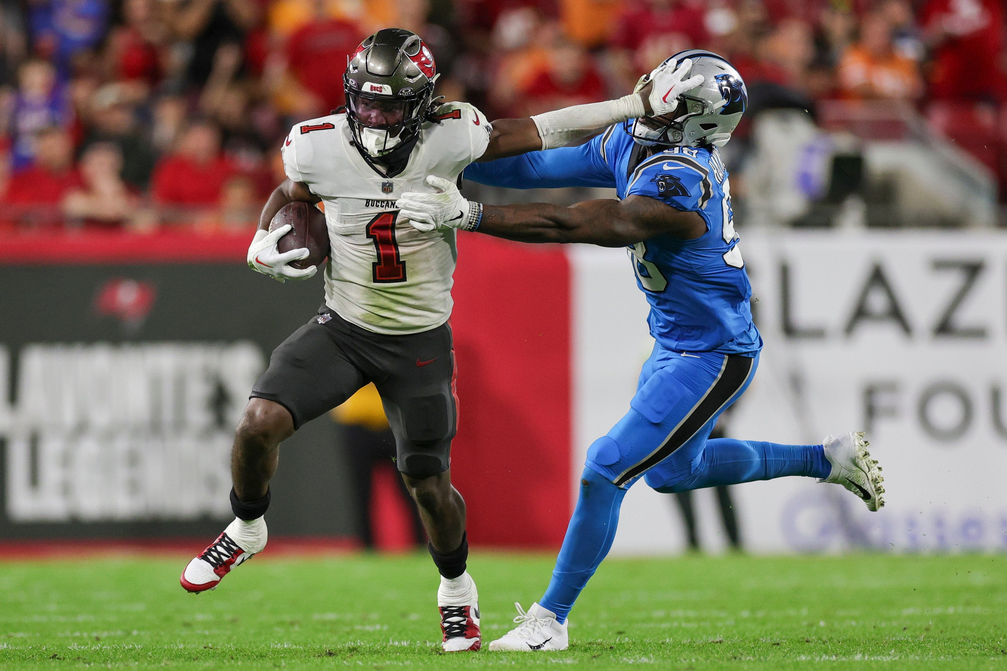 Dec 3, 2023; Tampa, Florida, USA; Tampa Bay Buccaneers running back Rachaad White (1) holds off Carolina Panthers linebacker Marquis Haynes Sr. (98) in the third quarter at Raymond James Stadium.