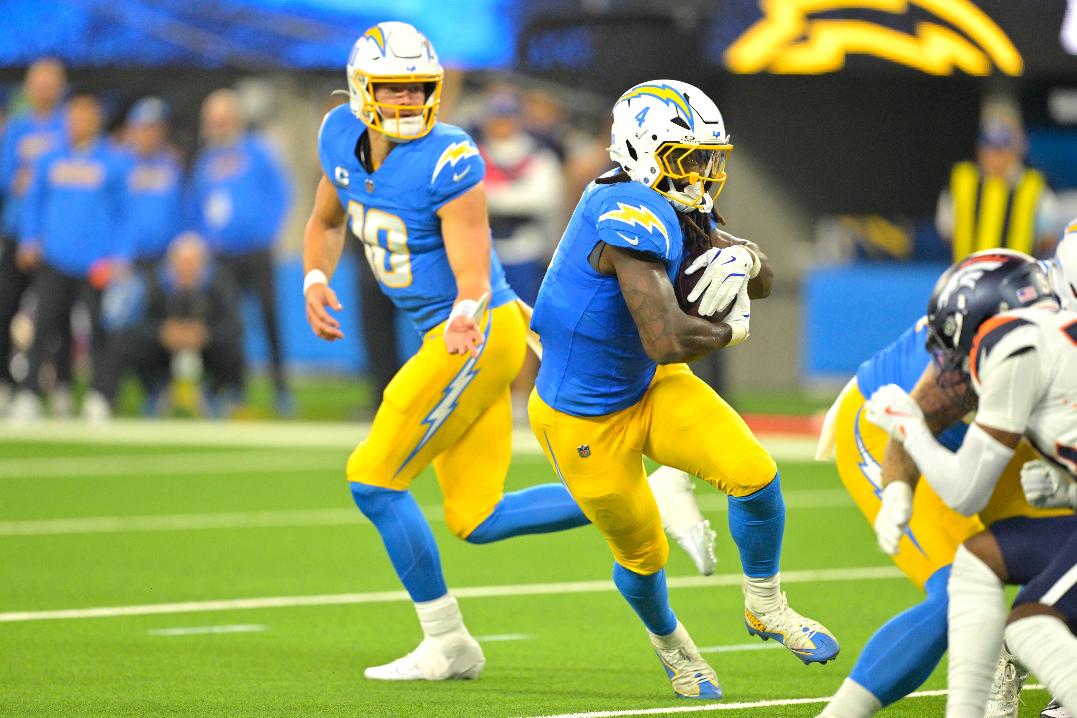 Chargers running back Gus Edwards (4) takes a hand off from quarterback Justin Herbert (10) and runs for a touchdown against the Broncos.