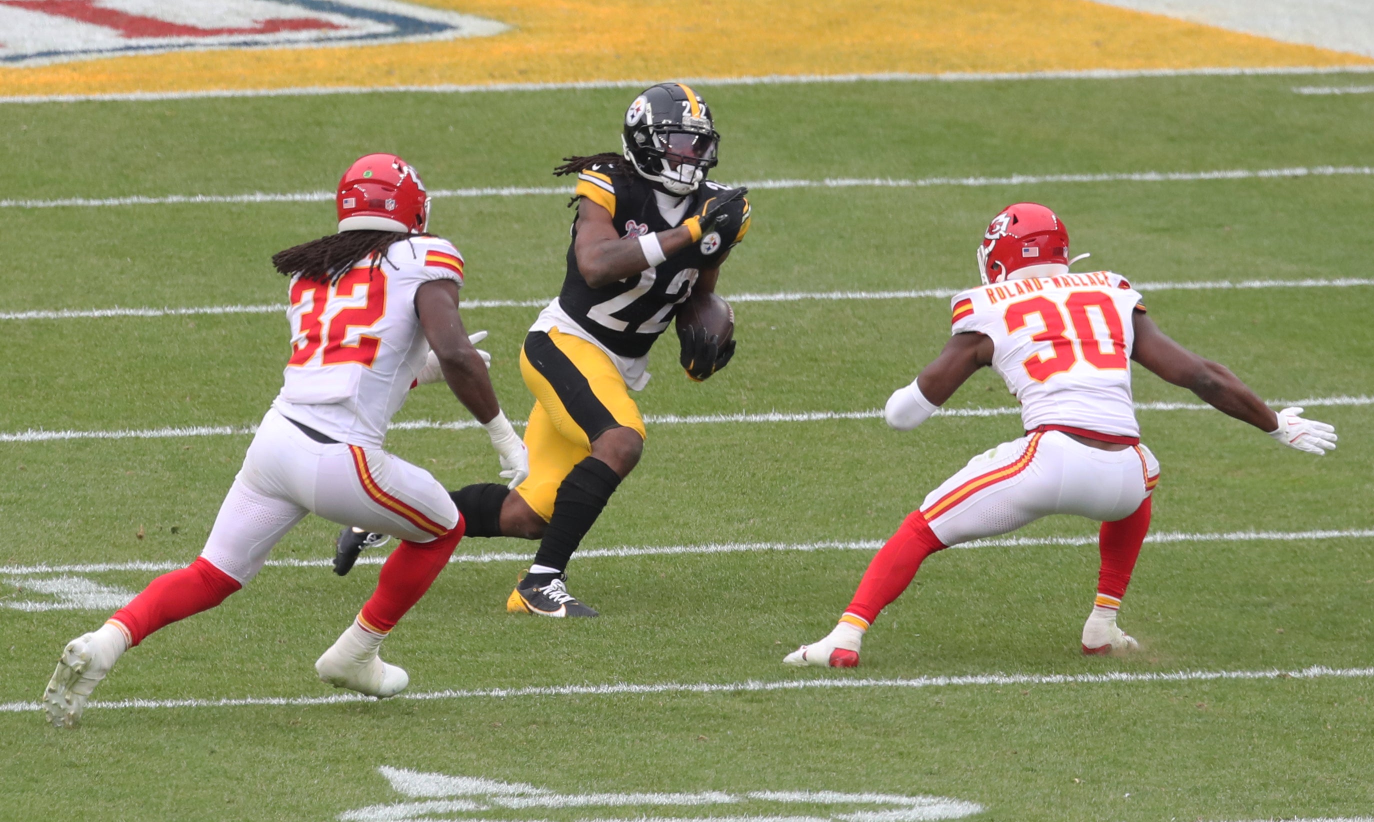Dec 25, 2024; Pittsburgh, Pennsylvania, USA; Pittsburgh Steelers running back Najee Harris (22) runs the ball as Kansas City Chiefs linebacker Nick Bolton (32) and cornerback Christian Roland-Wallace (30) defend during the third quarter at Acrisure Stadium.