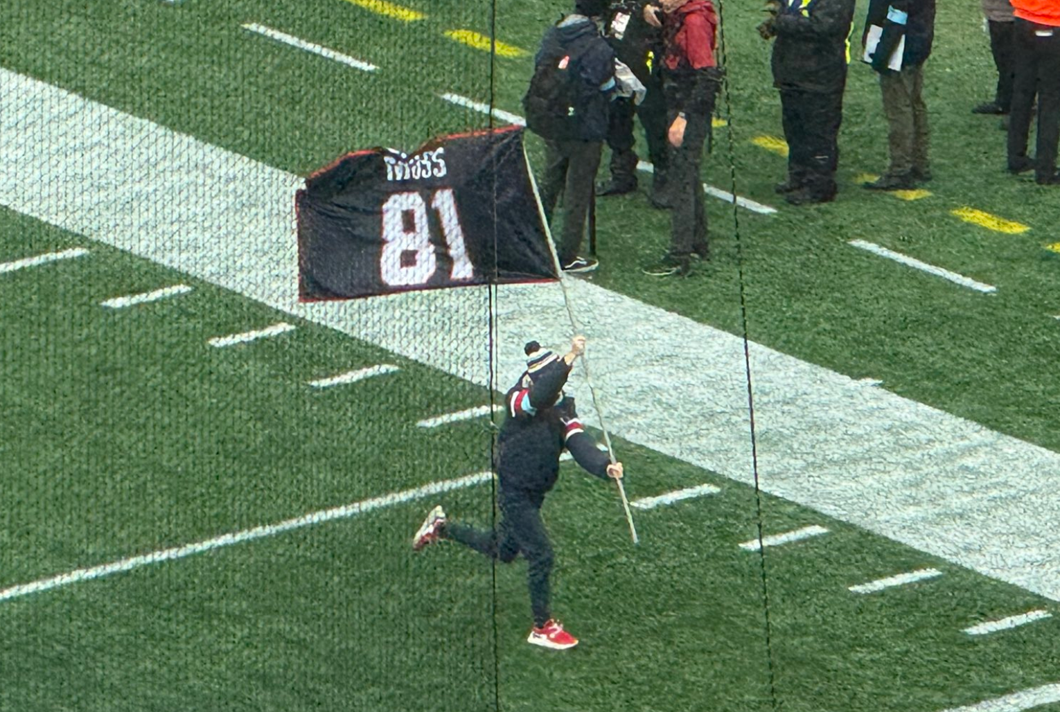 The Patriots run out onto the field on Saturday with a Randy Moss flag