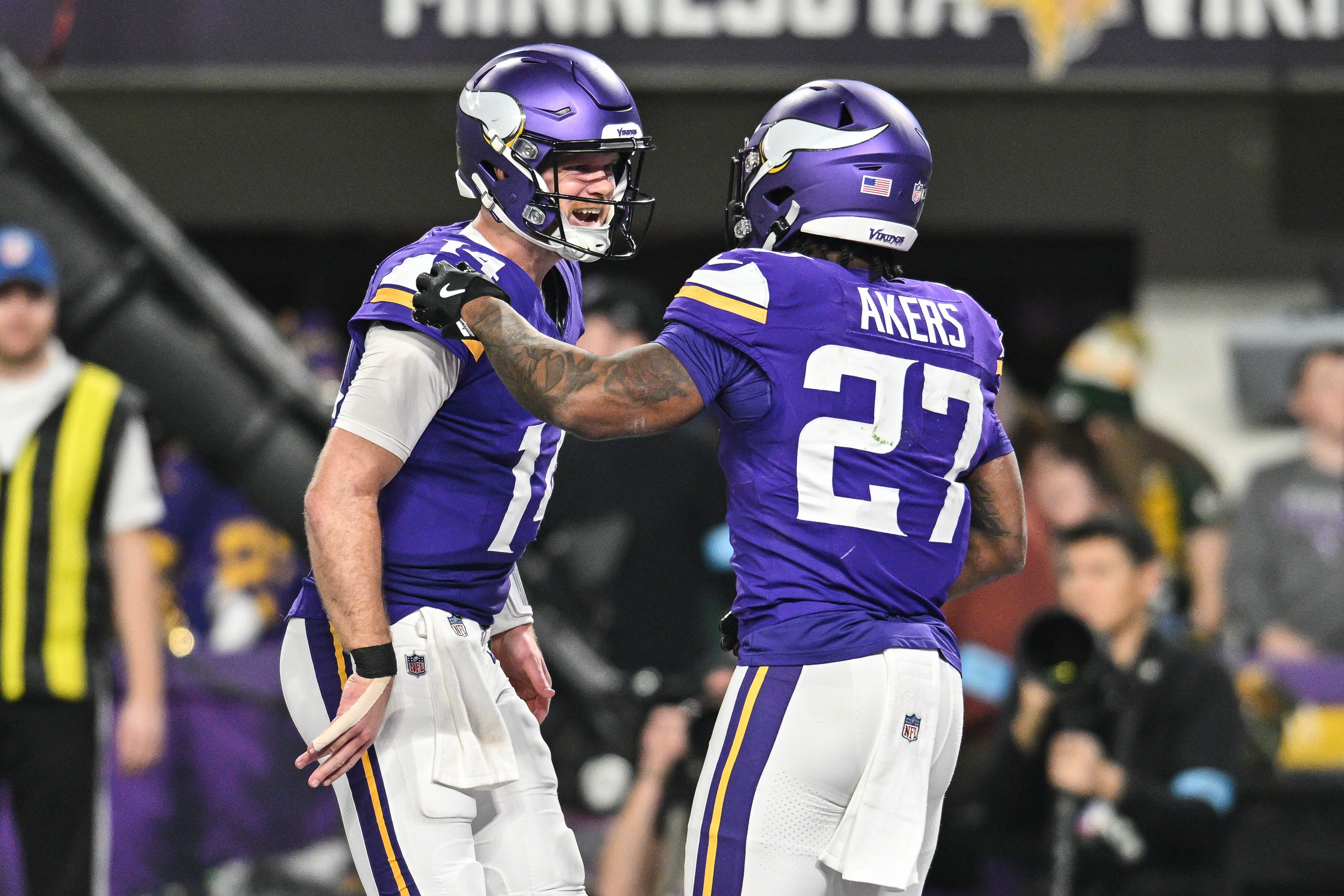 Dec 29, 2024; Minneapolis, Minnesota, USA; Minnesota Vikings quarterback Sam Darnold (14) reacts with running back Cam Akers (27) after a touchdown against the Green Bay Packers during the third quarter at U.S. Bank Stadium.