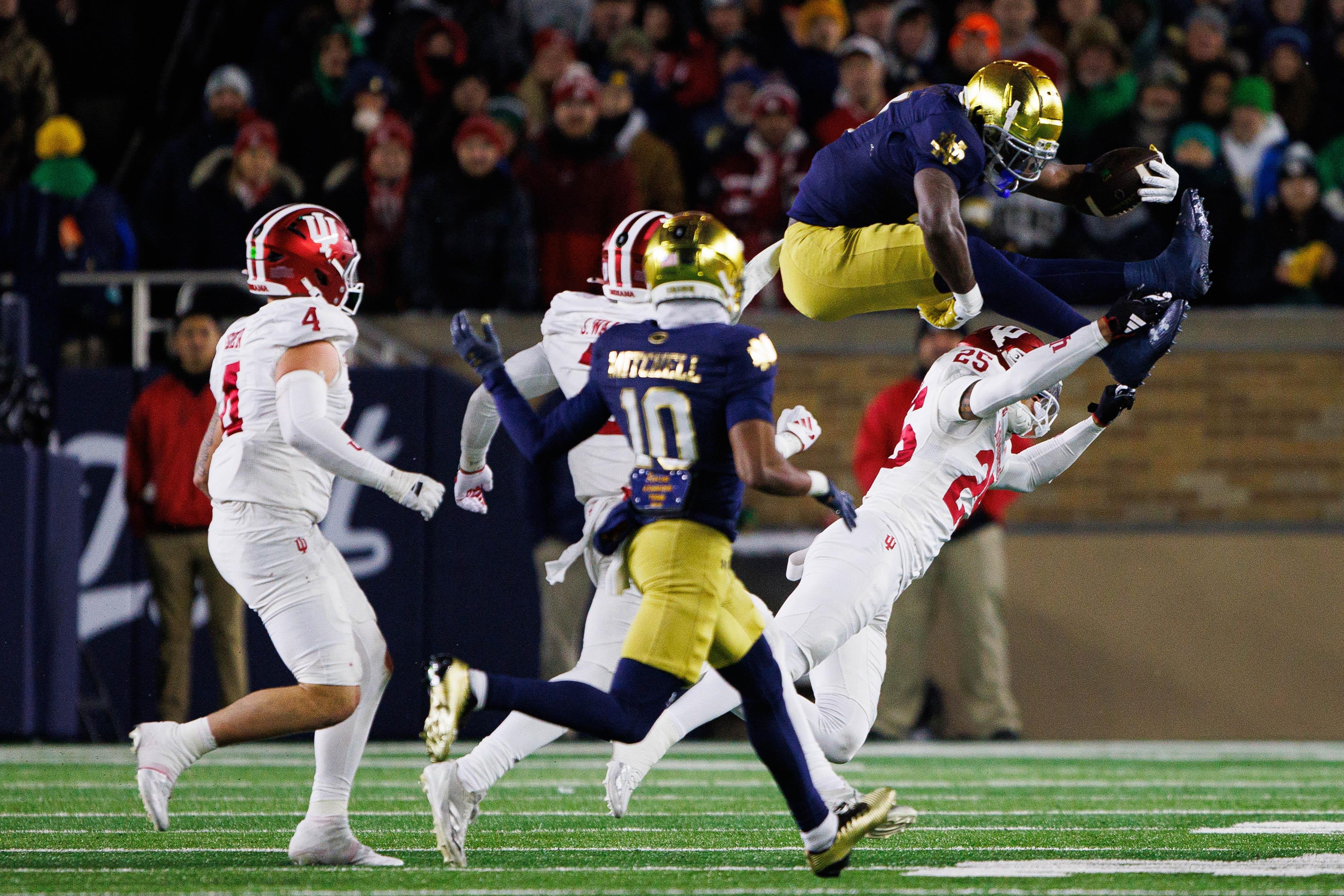 Notre Dame running back Jeremiyah Love (4) jumps over Indiana defensive back Amare Ferrell (25) during the first round of the College Football Playoff between Notre Dame and Indiana on Friday, Dec. 20, 2024, in South Bend.