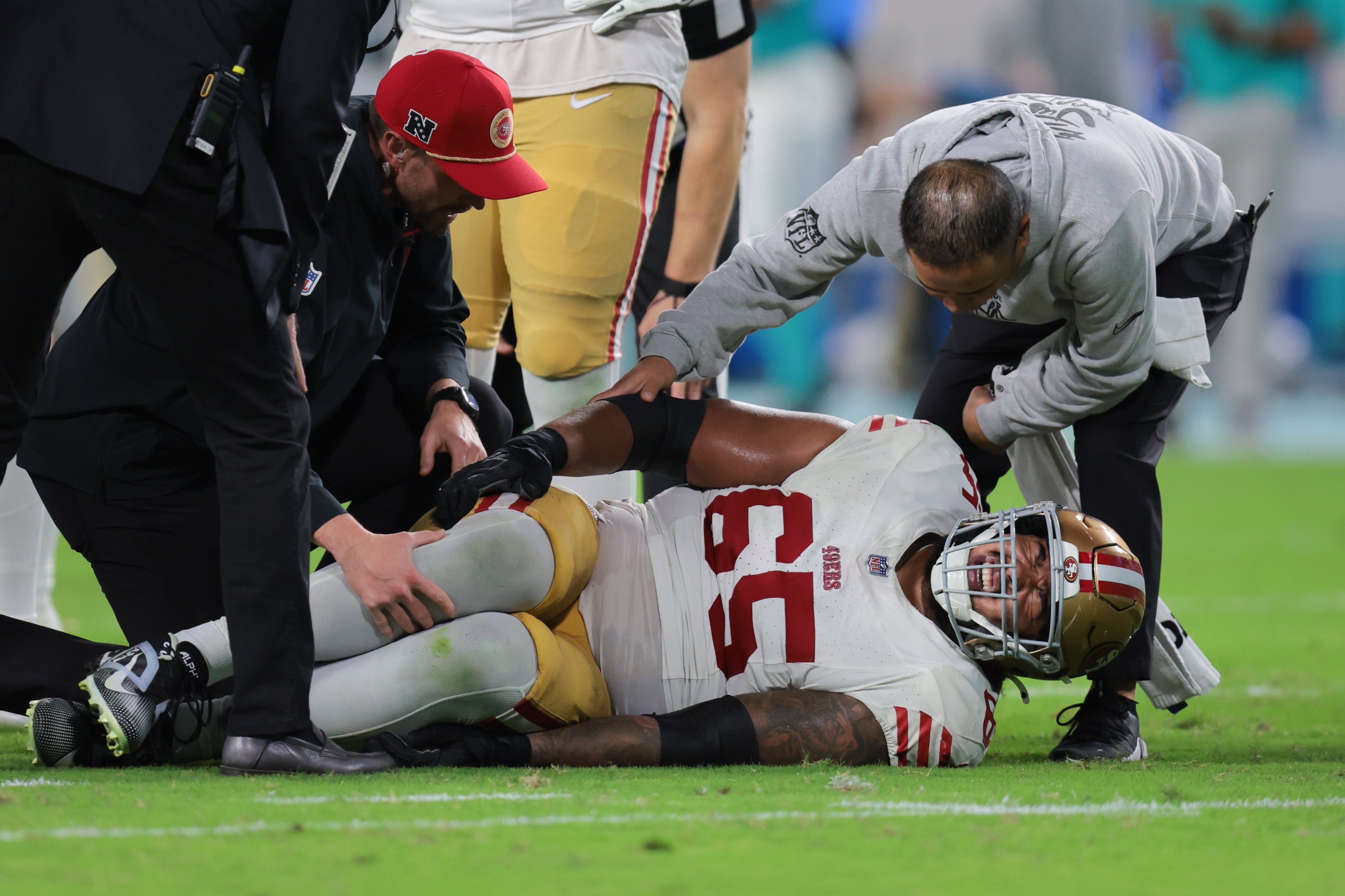 San Francisco 49ers guard Aaron Banks (65) is checked on by a trainer after an injury against the Miami Dolphins during the fourth quarter at Hard Rock Stadium.