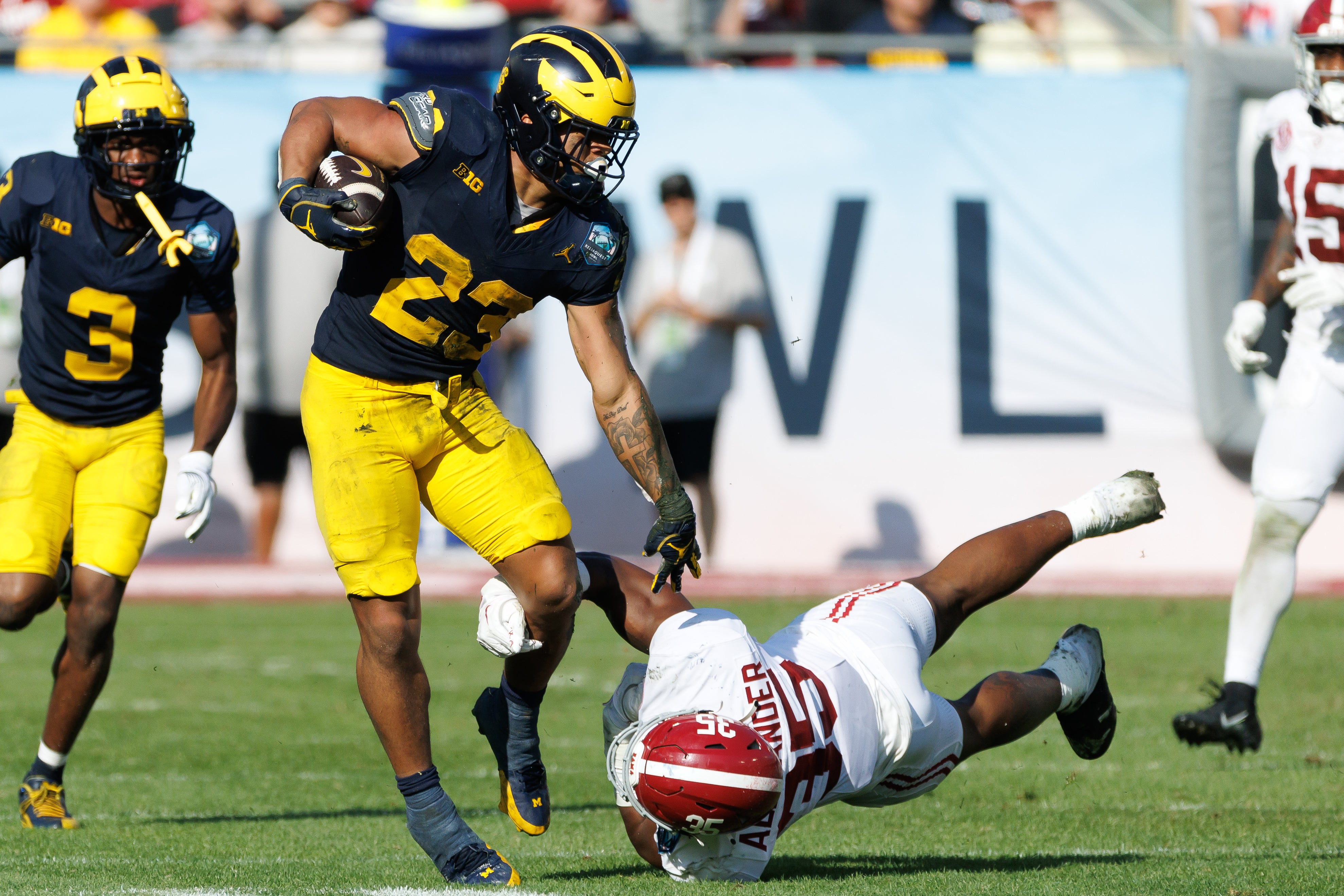 Dec 31, 2024; Tampa, FL, USA; Michigan Wolverines running back Jordan Marshall (23) pushes off on Alabama Crimson Tide linebacker Jeremiah Alexander (35) during the second half at Raymond James Stadium.