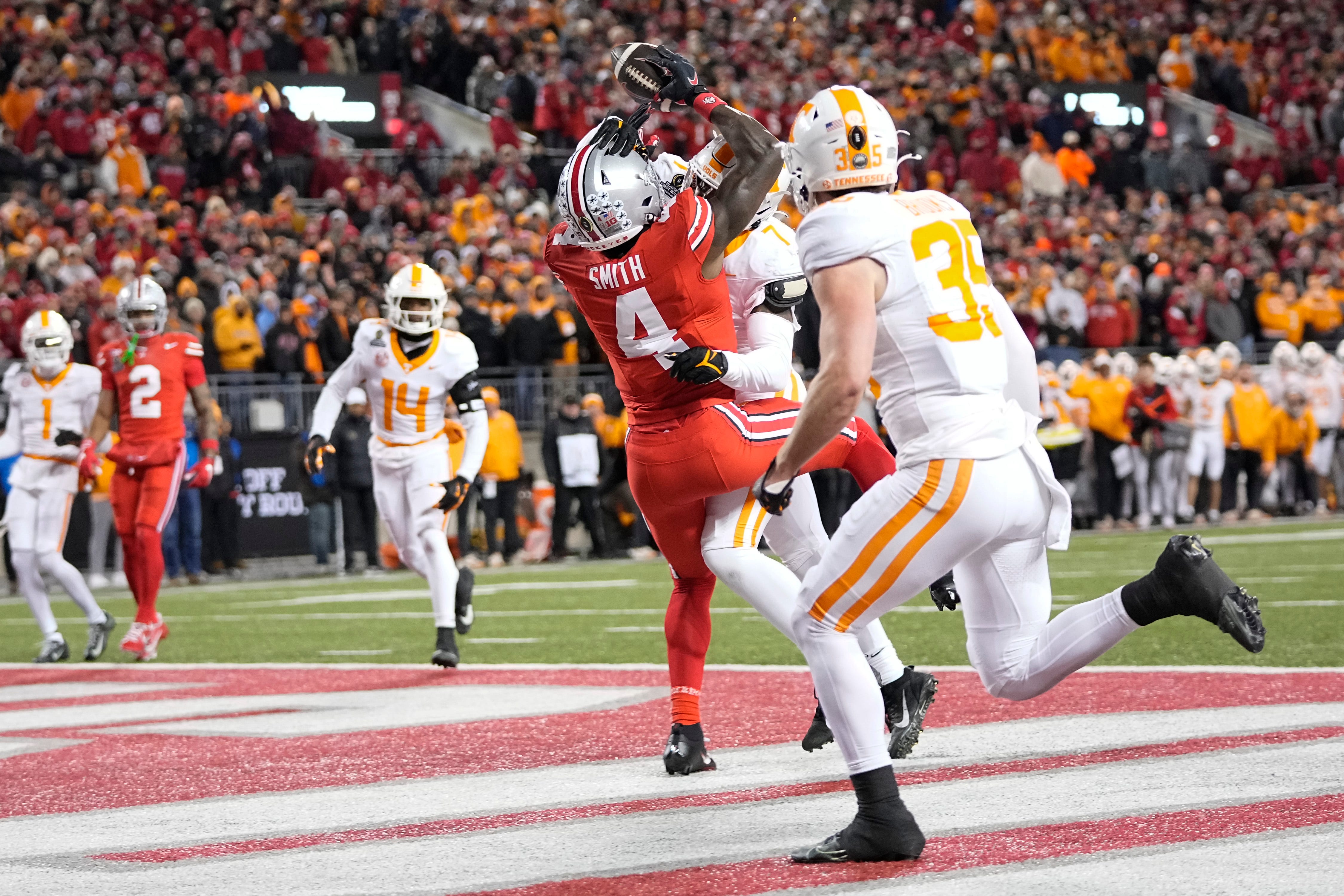 Ohio State Buckeyes wide receiver Jeremiah Smith (4) is hit by Tennessee Volunteers linebacker Arion Carter (7) resulting in an interception by defensive back Will Brooks (35) during the first half of the College Football Playoff first round game at Ohio Stadium in Columbus on Dec. 21, 2024.