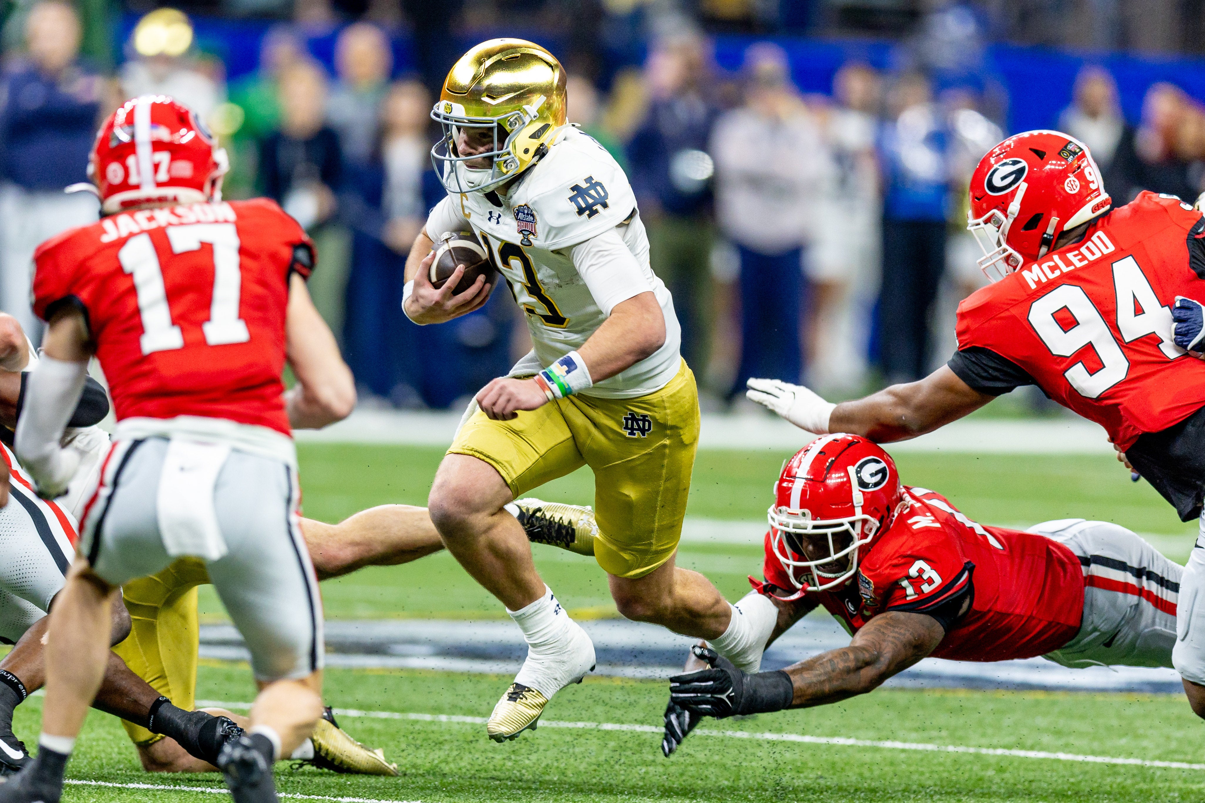 Notre Dame Fighting Irish quarterback Riley Leonard (13) scrambles out the pocket agains Georgia Bulldogs defensive lineman Mykel Williams (13) during the first half at Caesars Superdome.