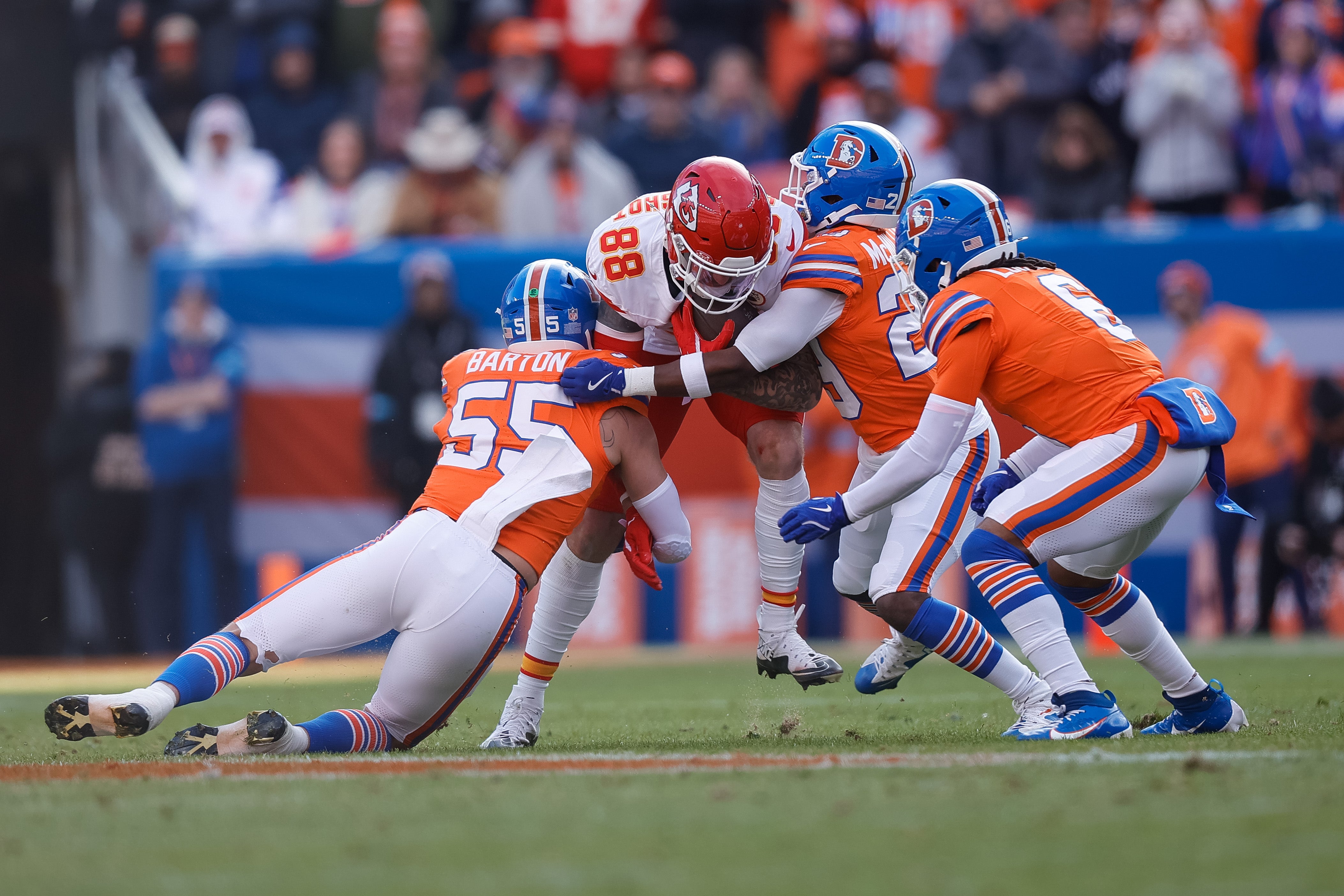 Jan 5, 2025; Denver, Colorado, USA; Kansas City Chiefs tight end Peyton Hendershot (88) is tackled by Denver Broncos linebacker Cody Barton (55) and cornerback Ja'Quan McMillian (29) and safety P.J. Locke (6) in the first quarter at Empower Field at Mile High.