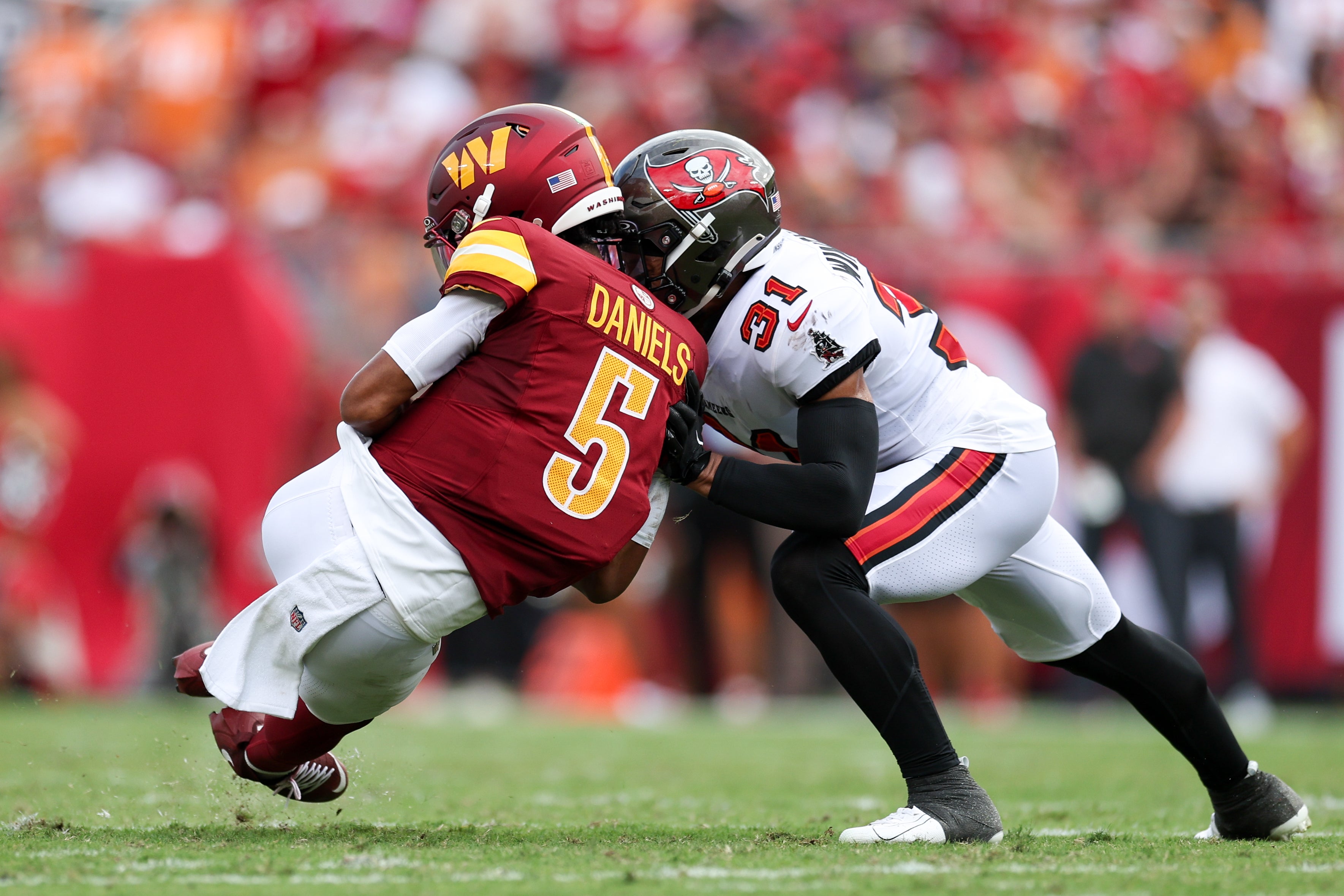 Sep 8, 2024; Tampa, Florida, USA; Washington Commanders quarterback Jayden Daniels (5) is hit by Tampa Bay Buccaneers safety Antoine Winfield Jr. (31) in the second quarter at Raymond James Stadium.