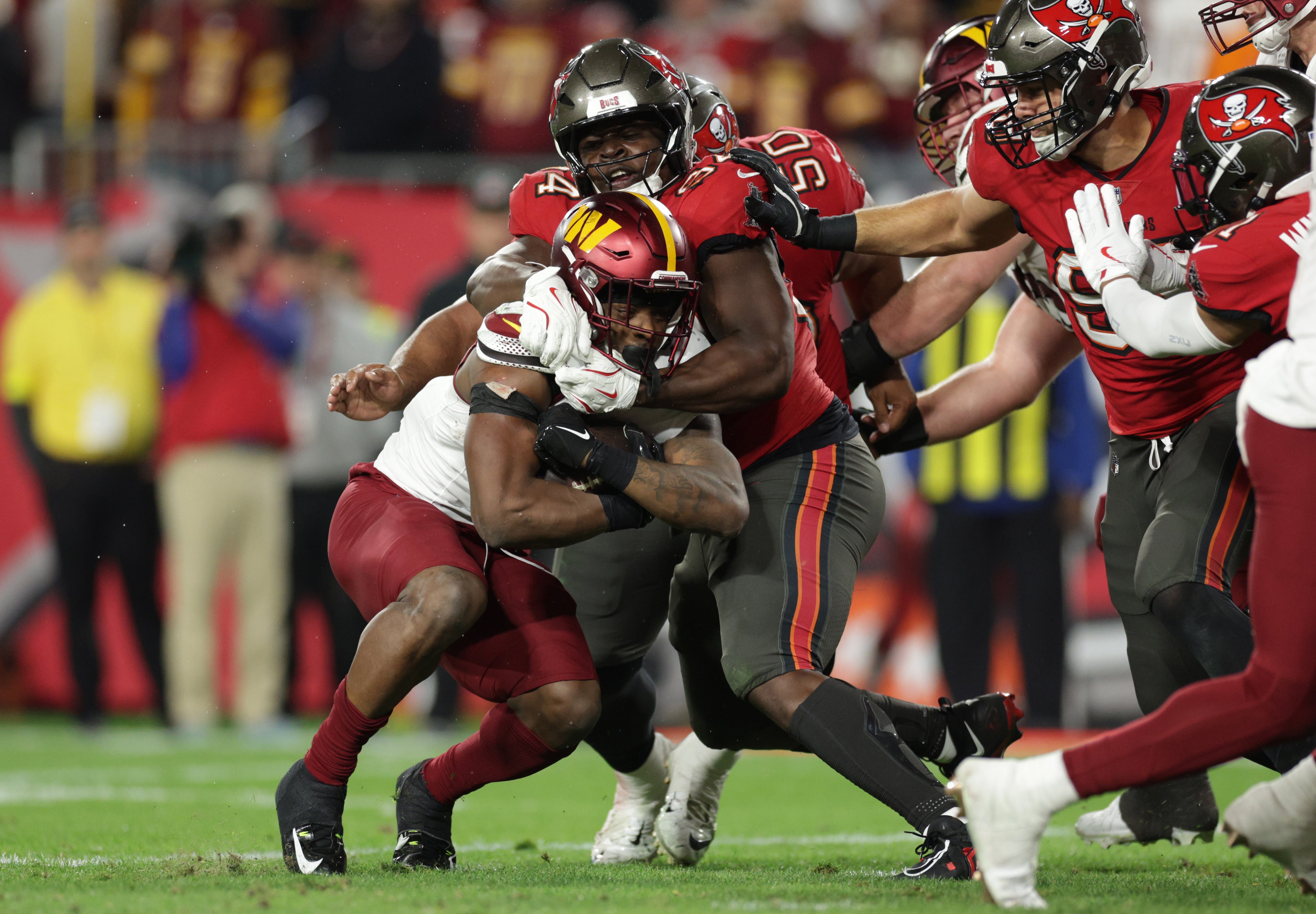 Jan 12, 2025; Tampa, Florida, USA; Tampa Bay Buccaneers defensive tackle Calijah Kancey (94) tackles Washington Commanders running back Brian Robinson Jr. (8) during the fourth quarter of a NFC wild card playoff at Raymond James Stadium.