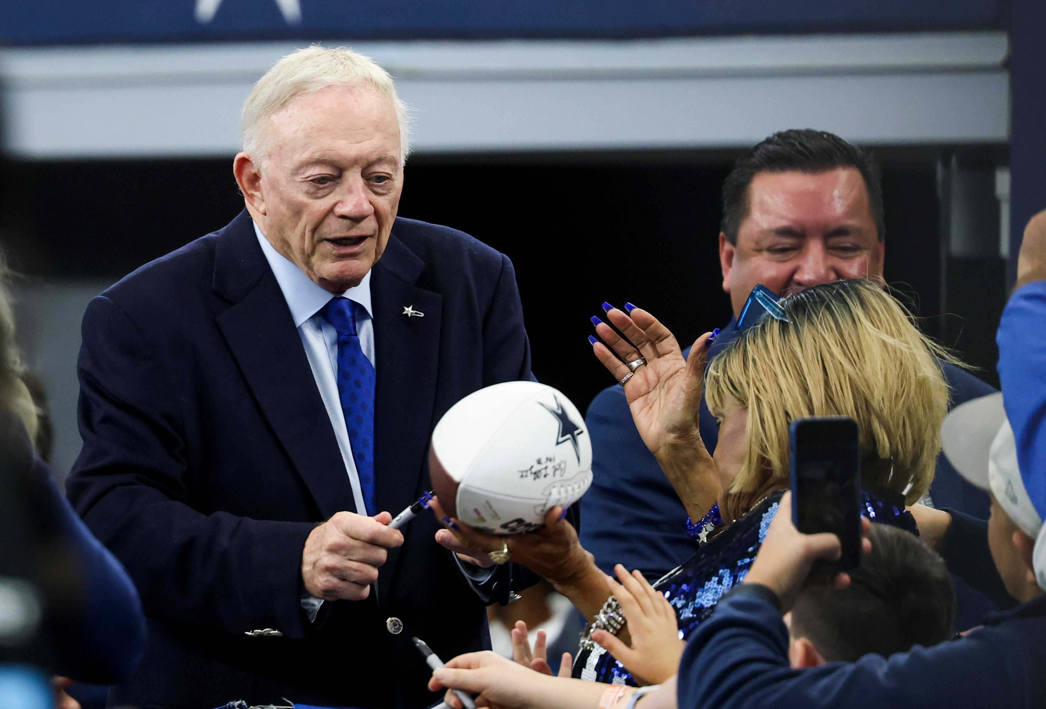 Dallas Cowboys owner Jerry Jones signs autographs before the game against the Washington Commanders at AT&T Stadium.