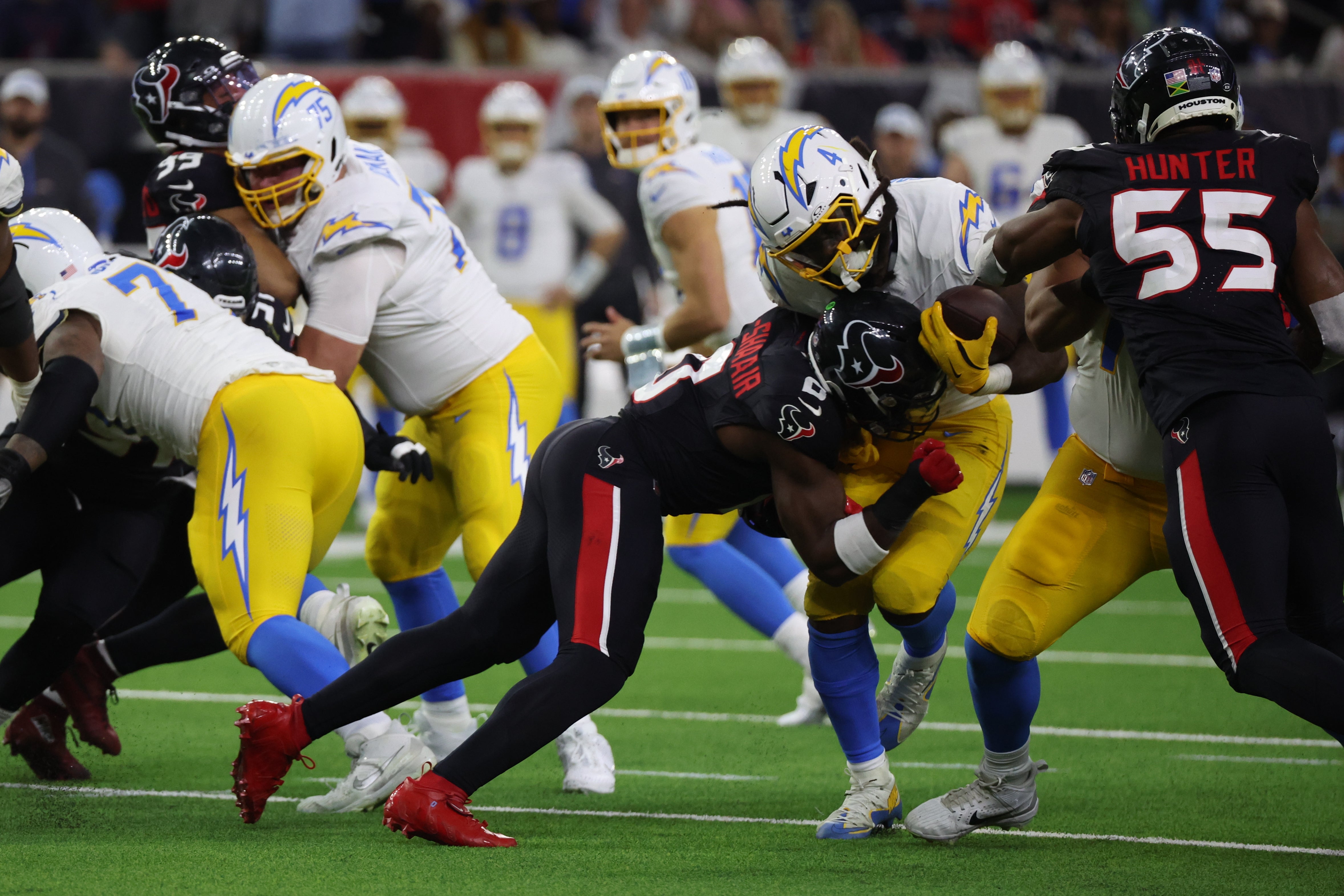 Jan 11, 2025; Houston, Texas, USA; Houston Texans linebacker Azeez Al-Shaair (0) tackles Los Angeles Chargers running back Gus Edwards (4) in the third quarter in an AFC wild card game at NRG Stadium.