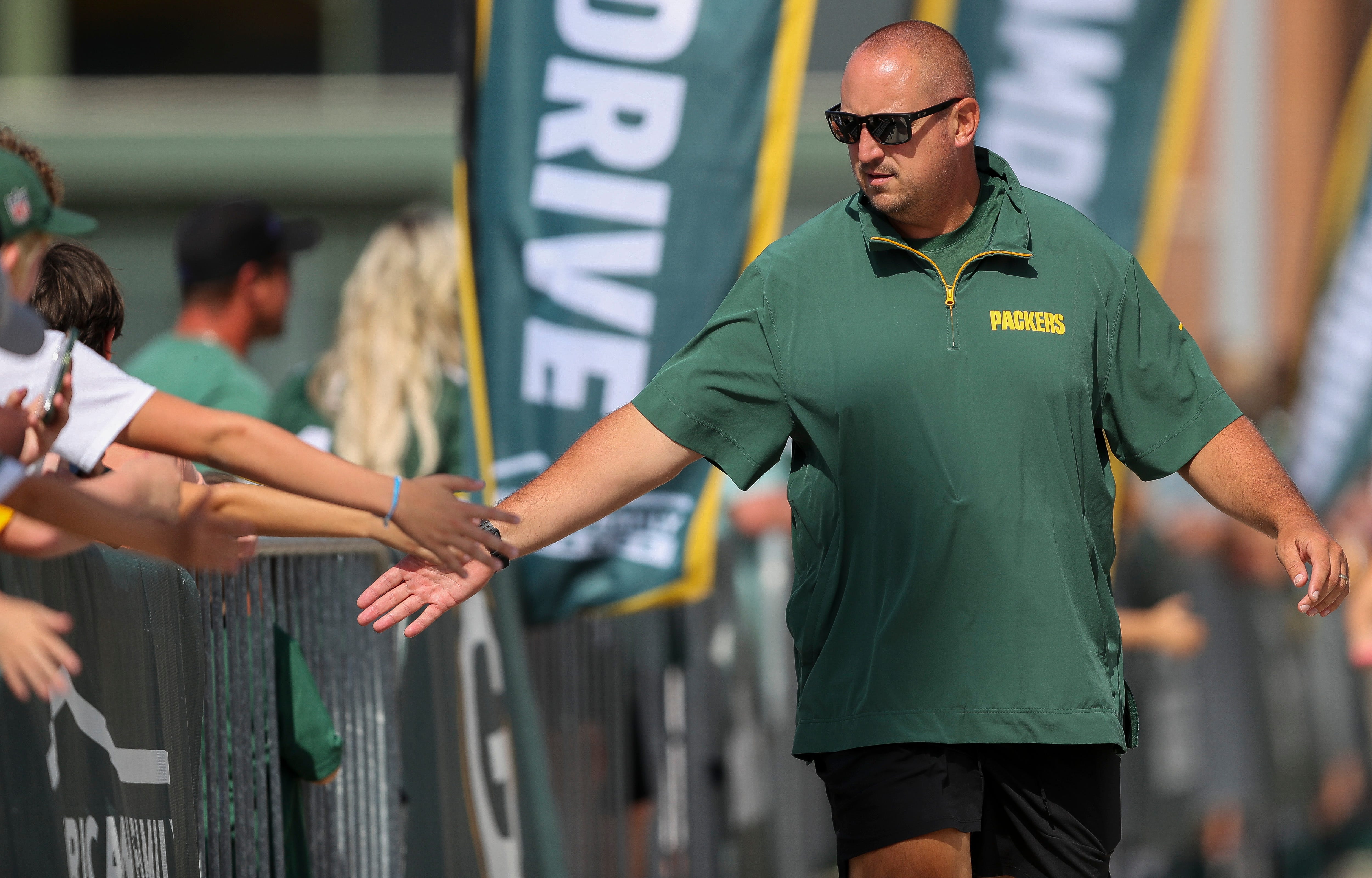 Green Bay Packers offensive coordinator Adam Stenavich slaps hands with fans as he walks to a joint practice with the Baltimore Ravens on Thursday, August 22, 2024, at Lambeau Field in Green Bay, Wis.