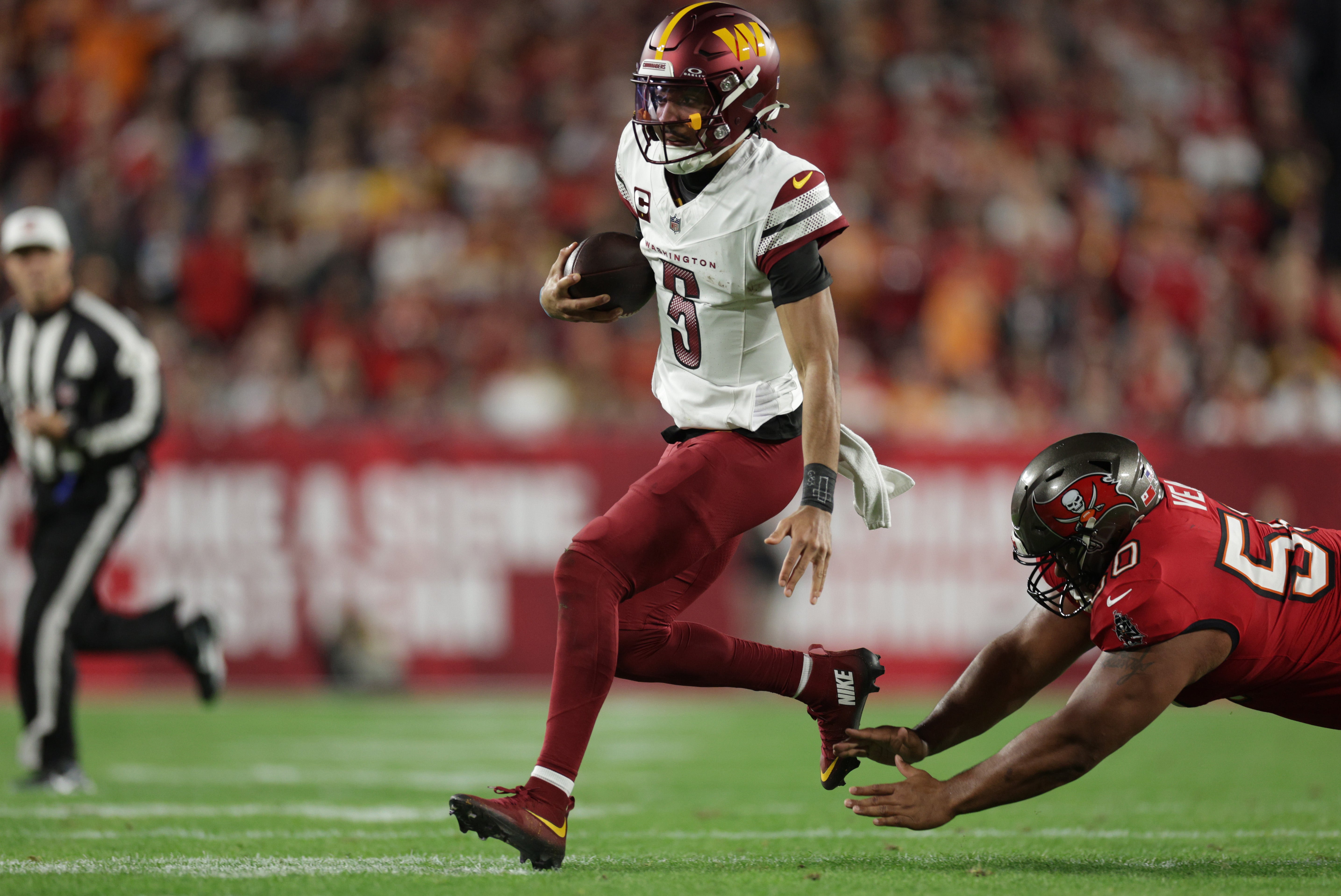 an 12, 2025; Tampa, Florida, USA; Washington Commanders quarterback Jayden Daniels (5) scrambles against Tampa Bay Buccaneers defensive tackle Vita Vea (50) during the second quarter of a NFC wild card playoff at Raymond James Stadium.