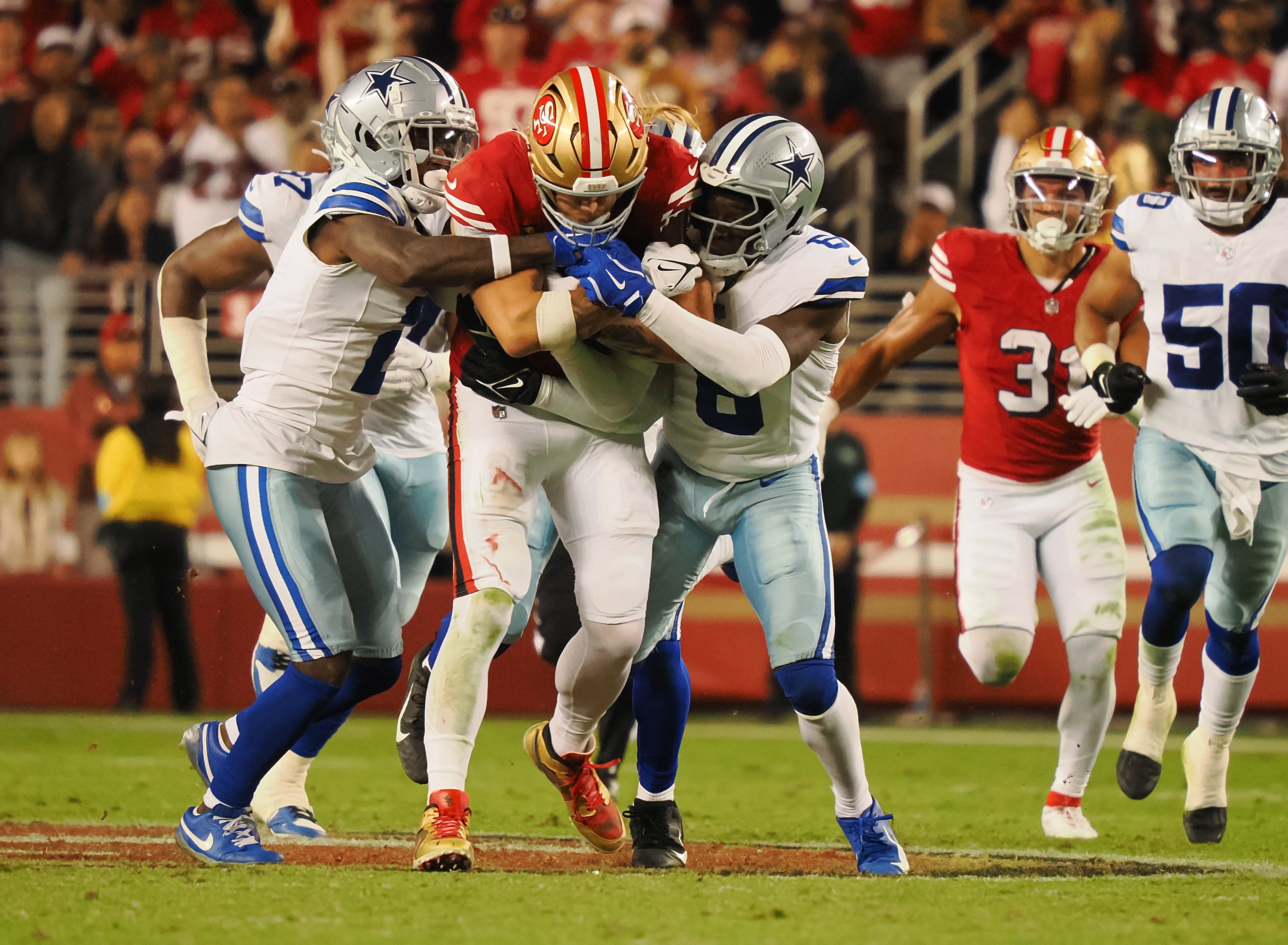 San Francisco 49ers tight end George Kittle (85) carries the ball between two Dallas Cowboys defenders during the second quarter at Levi's Stadium.