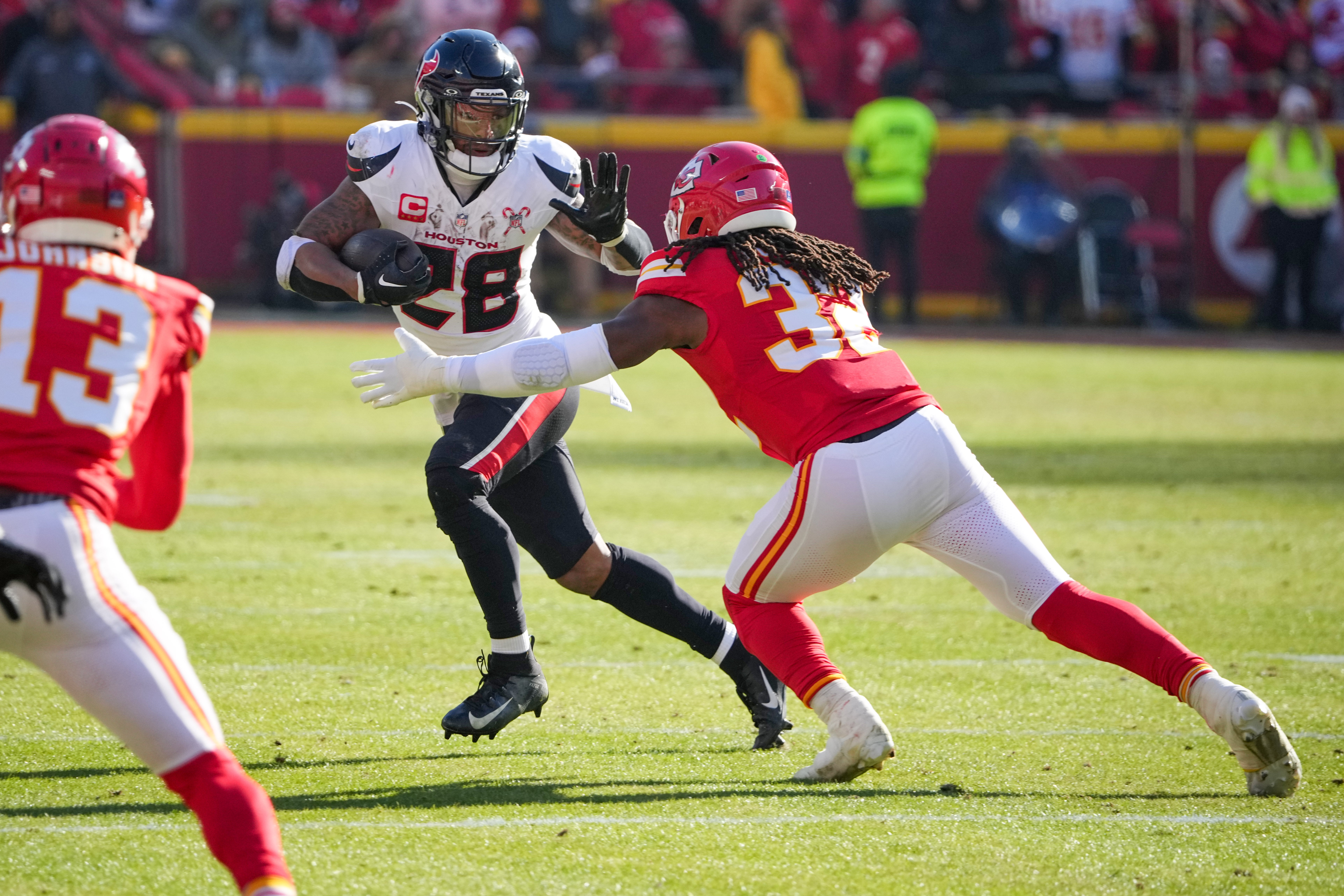 Dec 21, 2024; Kansas City, Missouri, USA; Houston Texans running back Joe Mixon (28) runs the ball as Kansas City Chiefs linebacker Nick Bolton (32) defends during the first half at GEHA Field at Arrowhead Stadium.