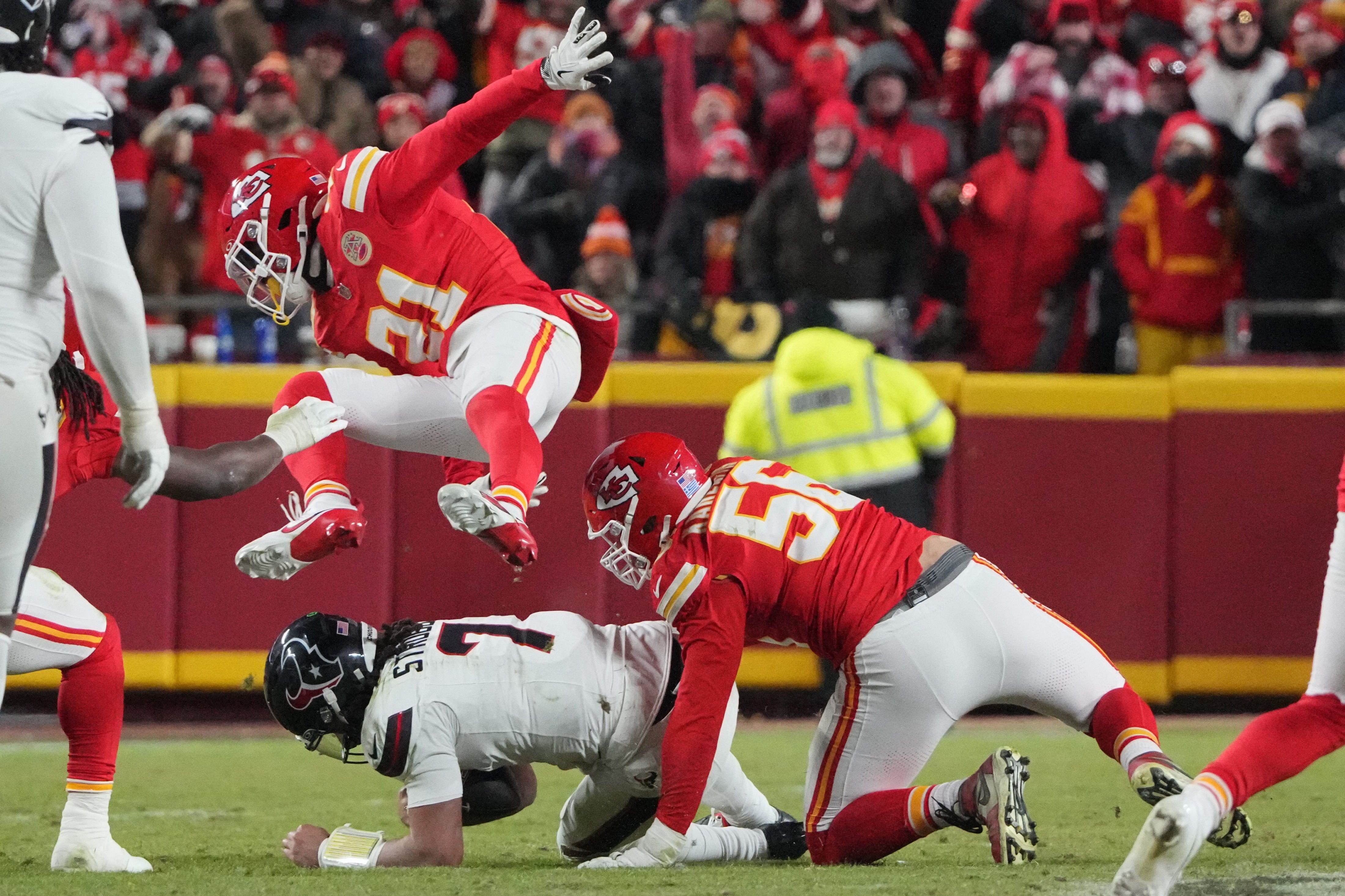Jan 18, 2025; Kansas City, Missouri, USA; Houston Texans quarterback C.J. Stroud (7) is sacked by Kansas City Chiefs defensive end George Karlaftis (56) as safety Jaden Hicks (21) jumps over the play during the fourth quarter of a 2025 AFC divisional round game at GEHA Field at Arrowhead Stadium.