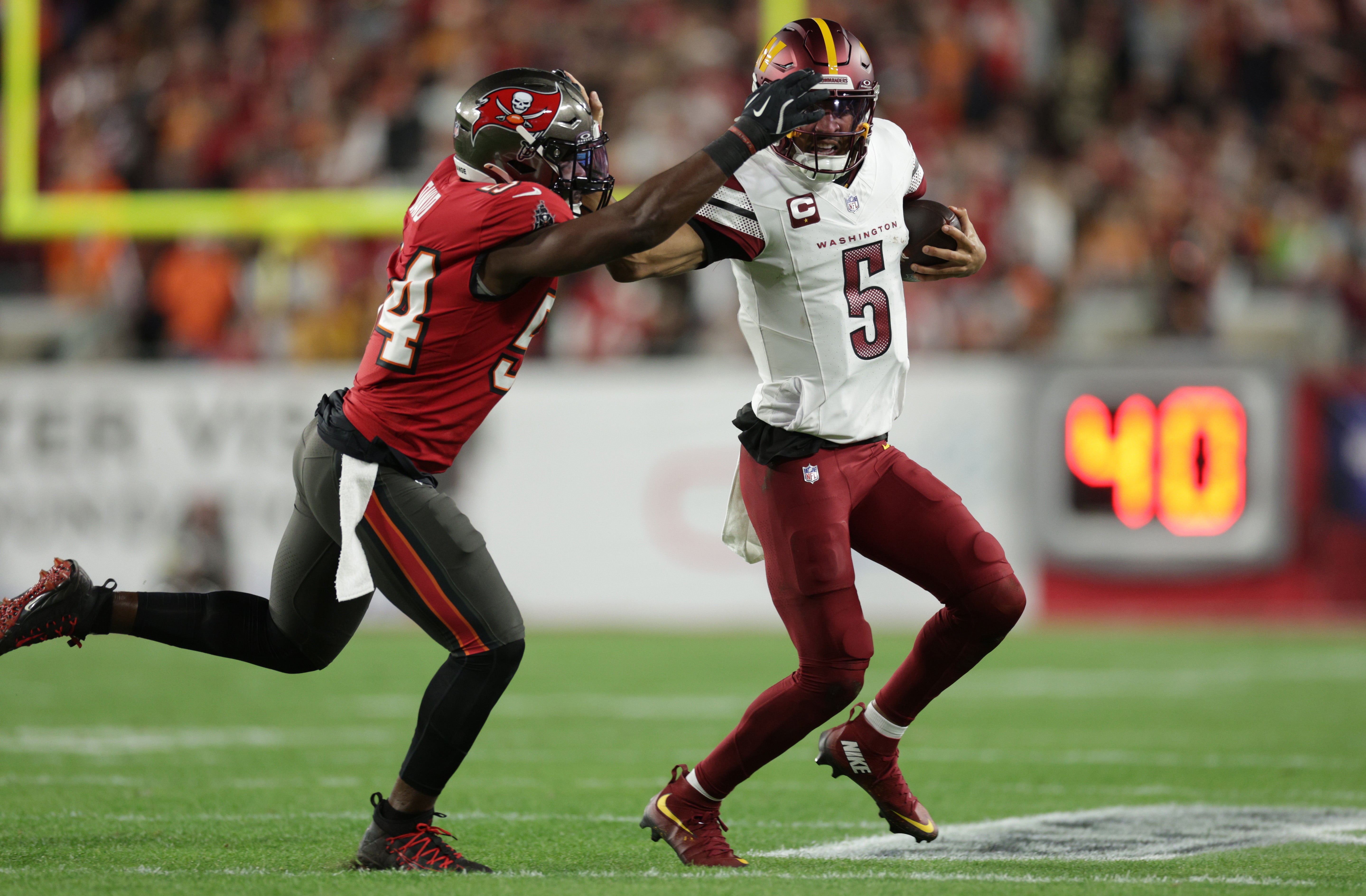 Jan 12, 2025; Tampa, Florida, USA; Washington Commanders quarterback Jayden Daniels (5) is tackled by Tampa Bay Buccaneers linebacker Lavonte David (54) during the first quarter of a NFC wild card playoff at Raymond James Stadium.