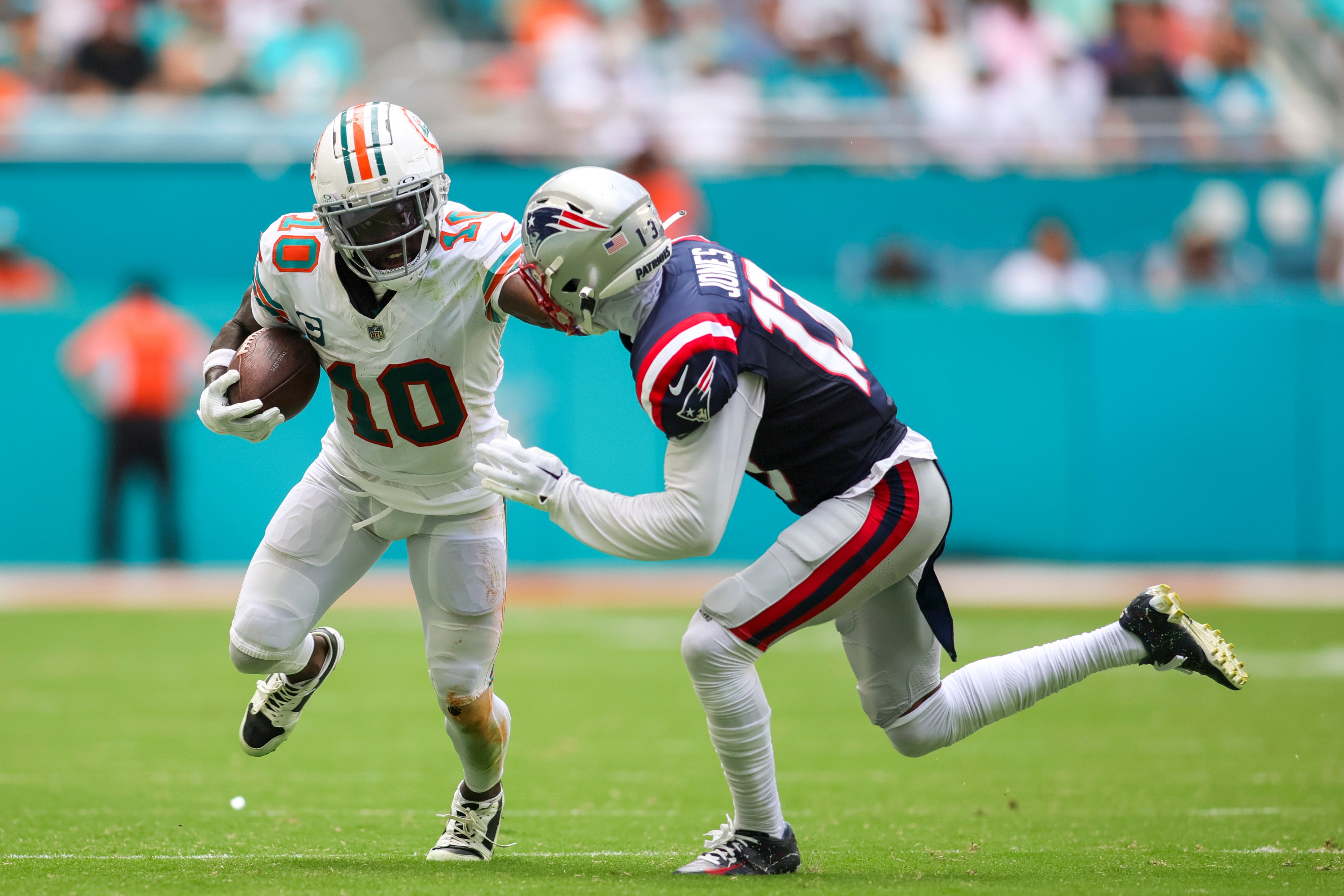 Oct 29, 2023; Miami Gardens, Florida, USA; Miami Dolphins wide receiver Tyreek Hill (10) runs with the football against New England Patriots cornerback Jack Jones (13) during the second quarter at Hard Rock Stadium.