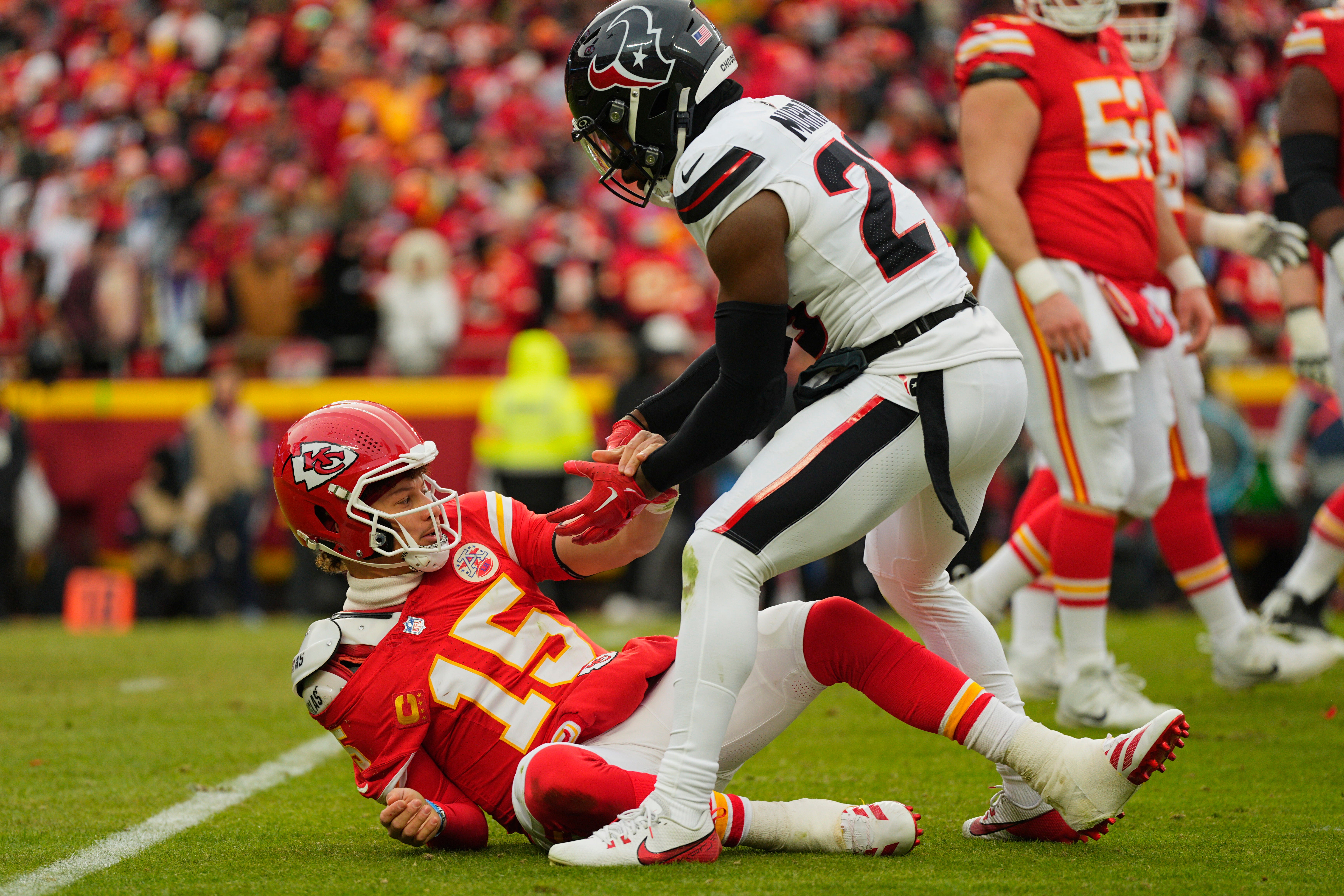 Jan 18, 2025; Kansas City, Missouri, USA; Houston Texans safety Eric Murray (23) assists Kansas City Chiefs quarterback Patrick Mahomes (15) up from the ground after a play during the second quarter of a 2025 AFC divisional round game at GEHA Field at Arrowhead Stadium.