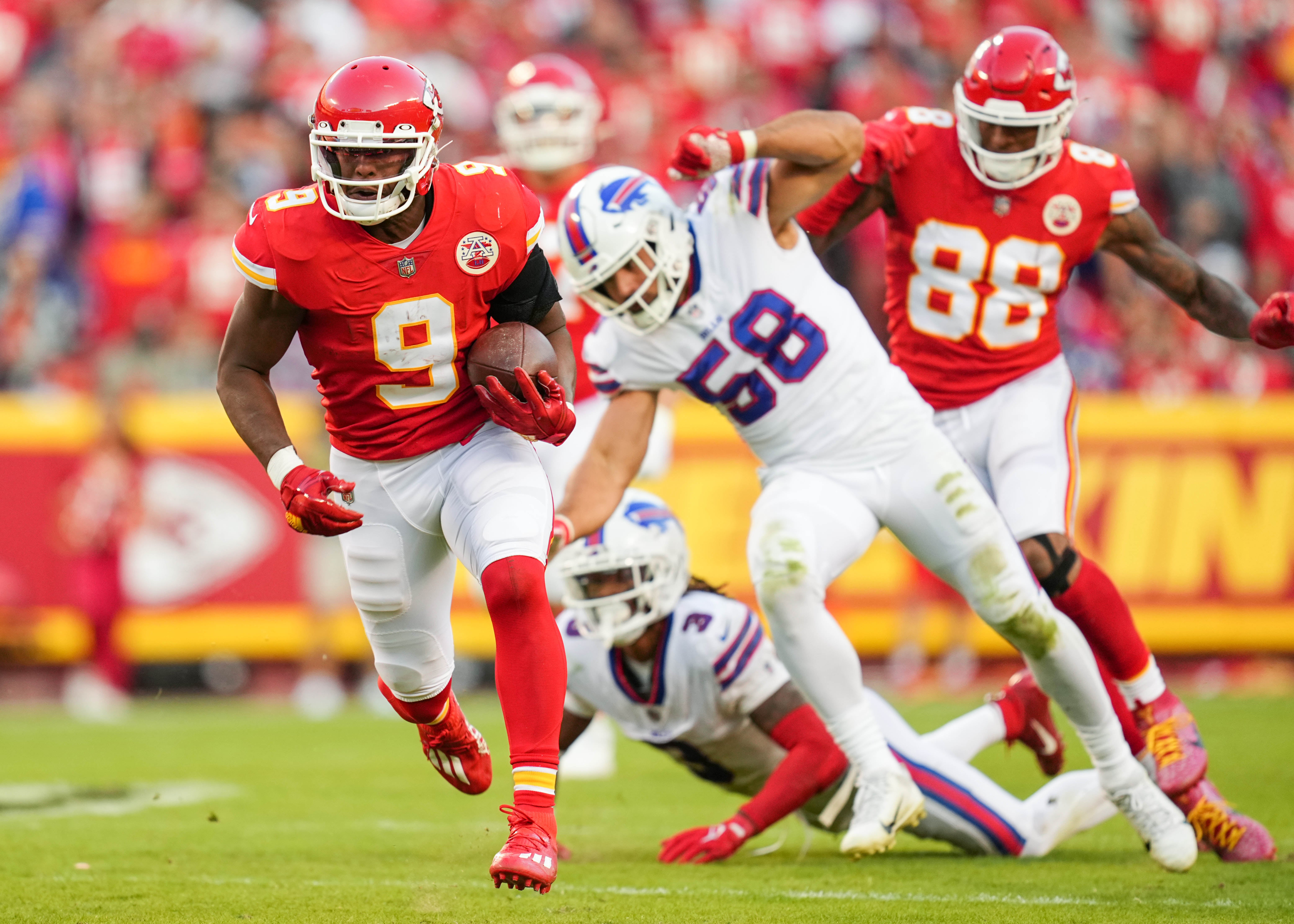 Oct 16, 2022; Kansas City, Missouri, USA; Kansas City Chiefs wide receiver JuJu Smith-Schuster (9) runs with the ball past Buffalo Bills linebacker Matt Milano (58) and safety Damar Hamlin (3) during the second half at GEHA Field at Arrowhead Stadium.