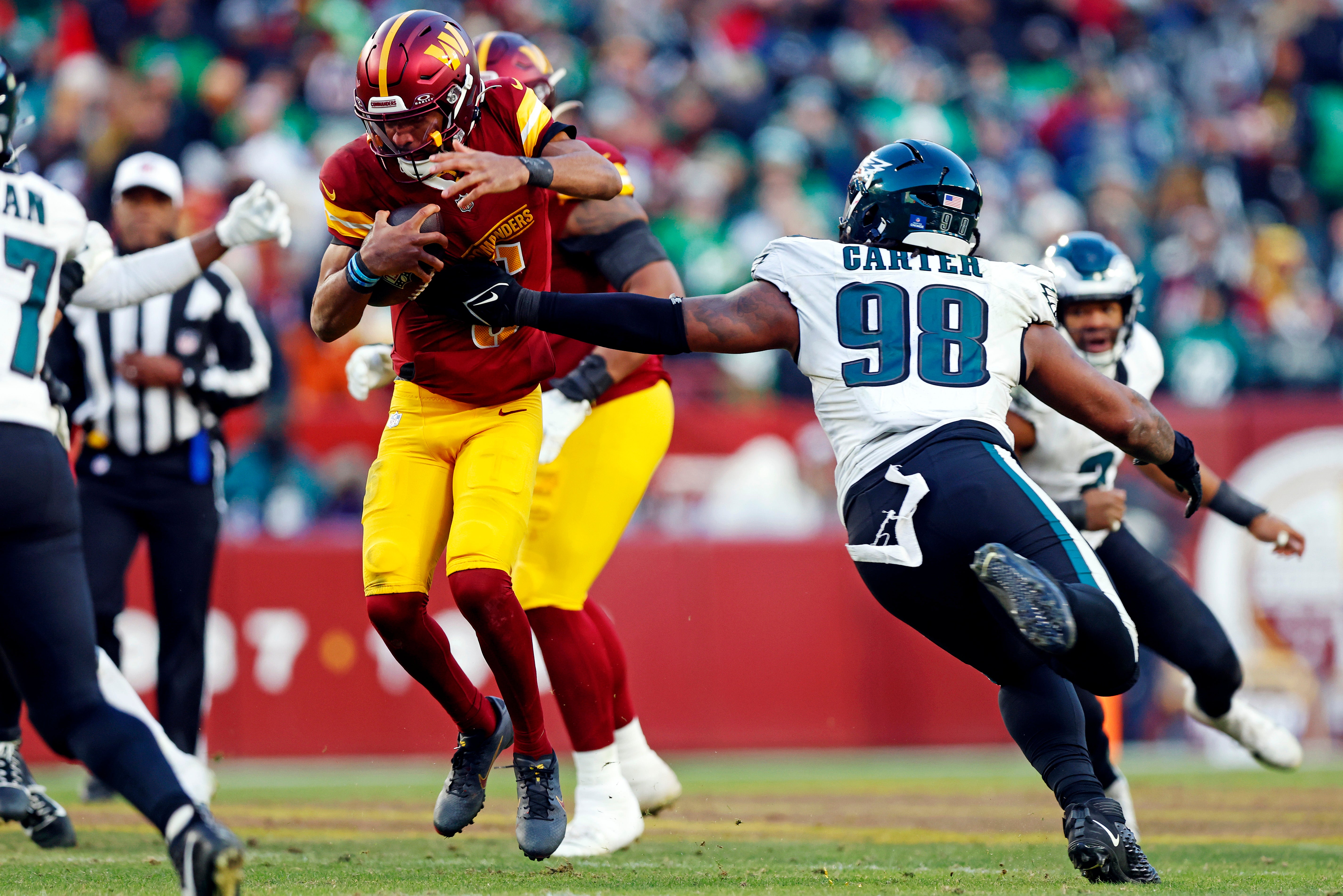 Washington Commanders quarterback Jayden Daniels (5) runs the ball against Philadelphia Eagles defensive tackle Jalen Carter (98) during the fourth quarter at Northwest Stadium.