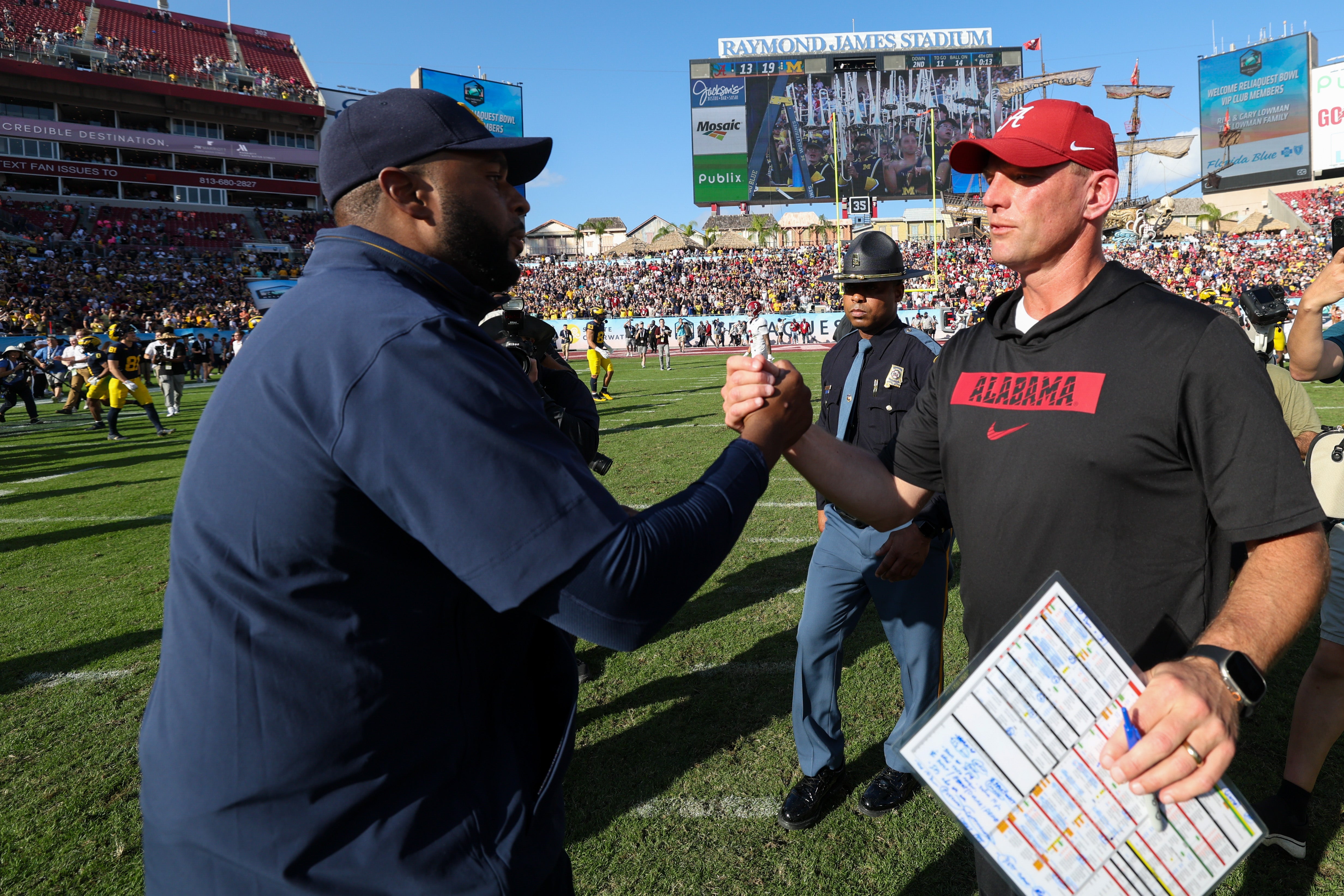 Dec 31, 2024; Tampa, FL, USA; Michigan Wolverines head coach Sherrone Moore greets Alabama Crimson Tide head coach Kalen Deboer after the ReliaQuest Bowl at Raymond James Stadium.