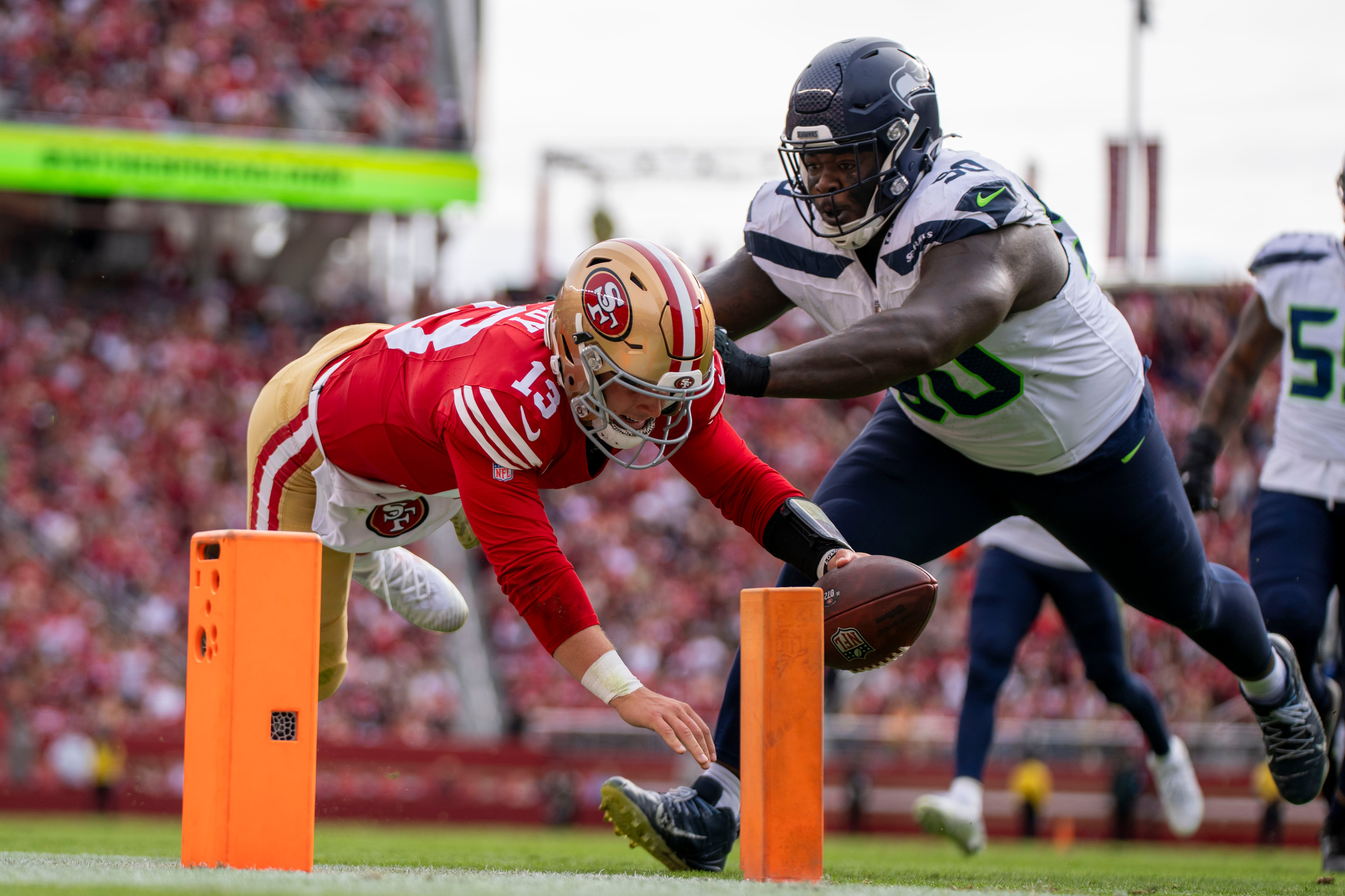 San Francisco 49ers quarterback Brock Purdy (13) scores a touchdown against Seattle Seahawks defensive tackle Jarran Reed (90) during the first quarter at Levi's Stadium.