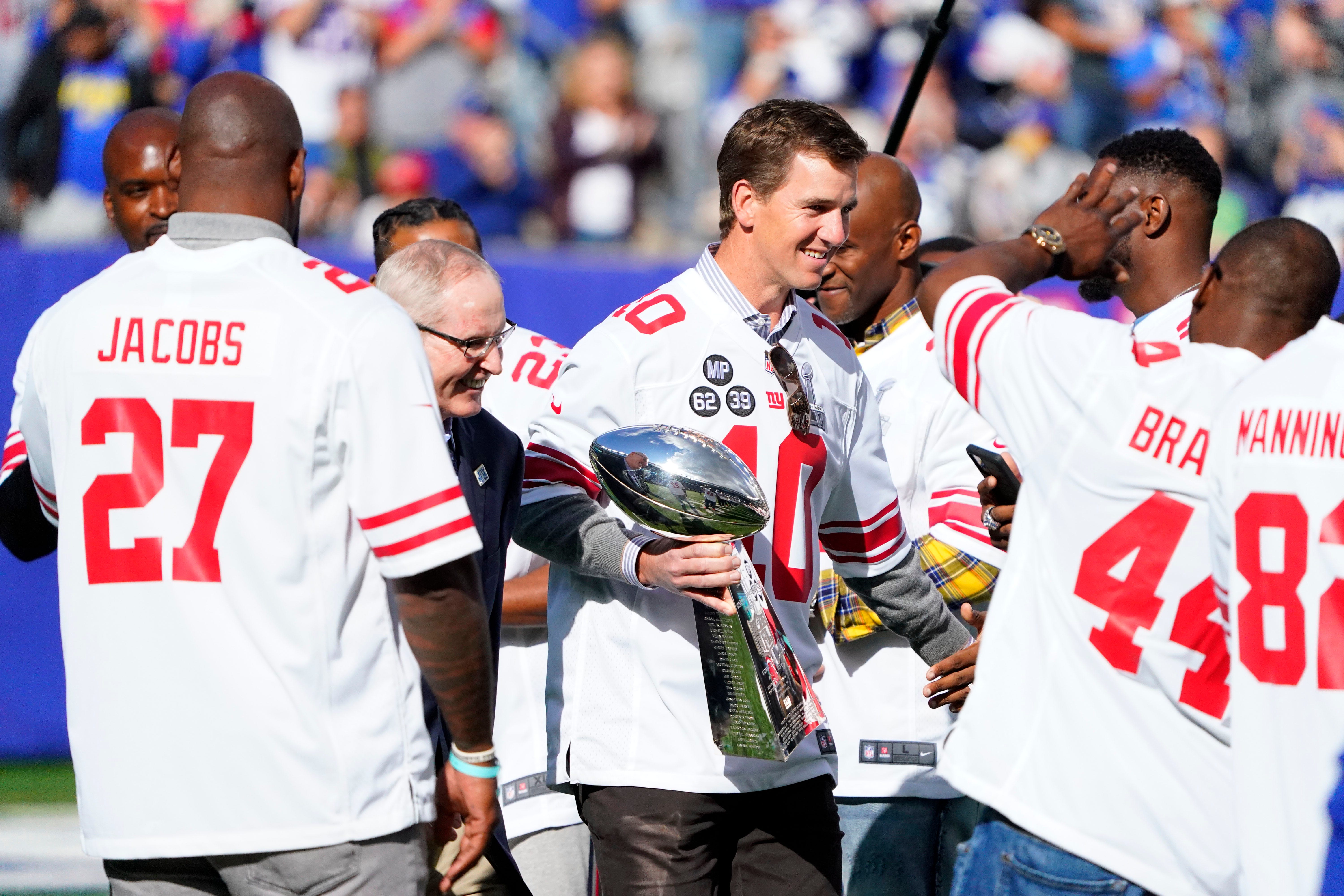 Oct 17, 2021; East Rutherford, NJ, USA; New York Giants former quarterback Eli Manning and head coach Tom Coughlin walk onto the field with the Vince Lombardi Trophy for a ceremony marking the 10 year anniversary of their Super Bowl win in 2011. The Giants fall to the Rams, 38-11, at MetLife Stadium on Sunday, Oct. 17, 2021, in East Rutherford. Mandatory Credit: Danielle Parhizkaran-Imagn Images