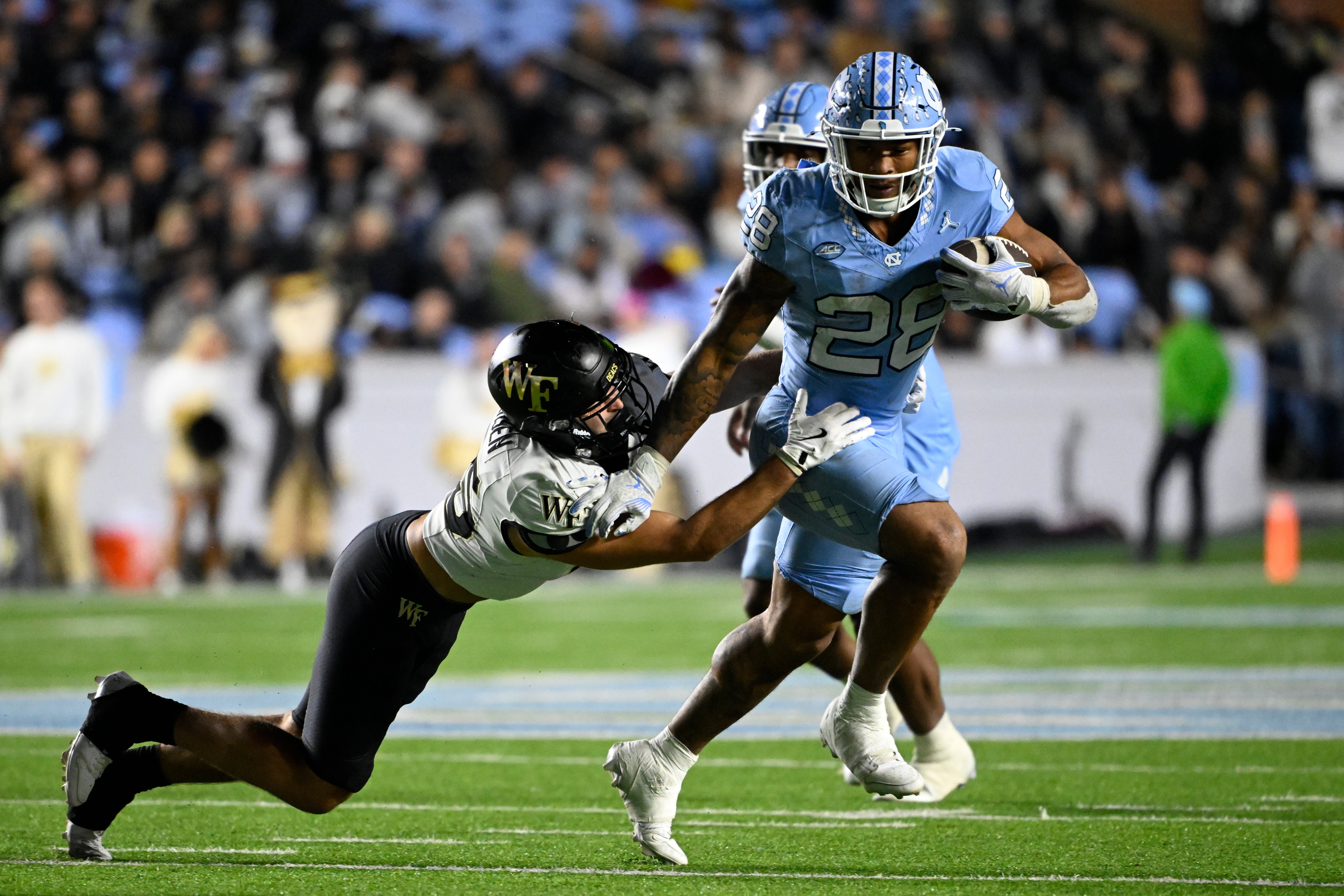 Nov 16, 2024; Chapel Hill, North Carolina, USA; North Carolina Tar Heels running back Omarion Hampton (28) runs as Wake Forest Demon Deacons defensive back Nick Andersen (45) defends in the third quarter at Kenan Memorial Stadium.