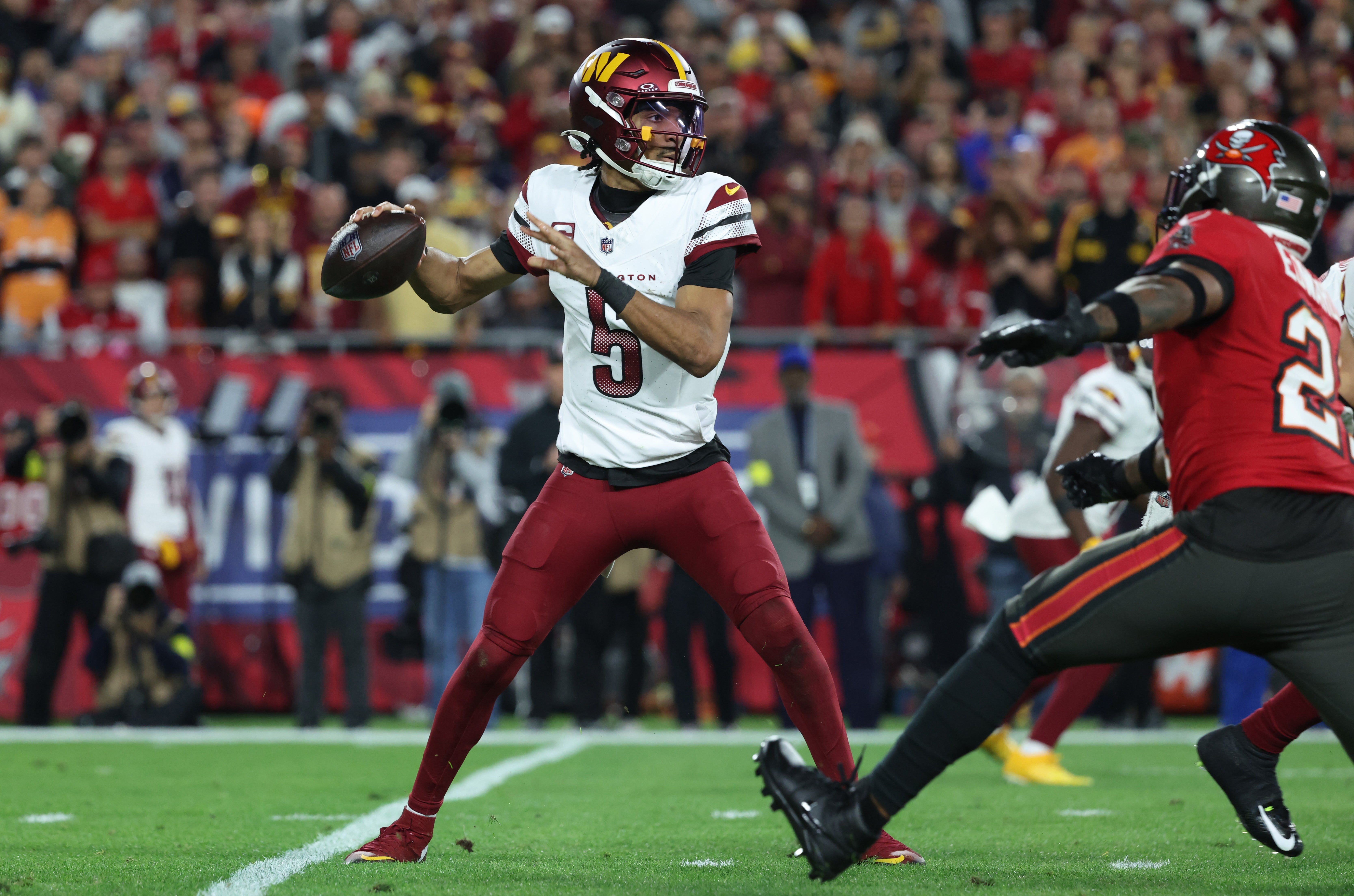 Jan 12, 2025; Tampa, Florida, USA; Washington Commanders quarterback Jayden Daniels (5) throws during the second quarter of a NFC wild card playoff against the Tampa Bay Buccaneers at Raymond James Stadium.